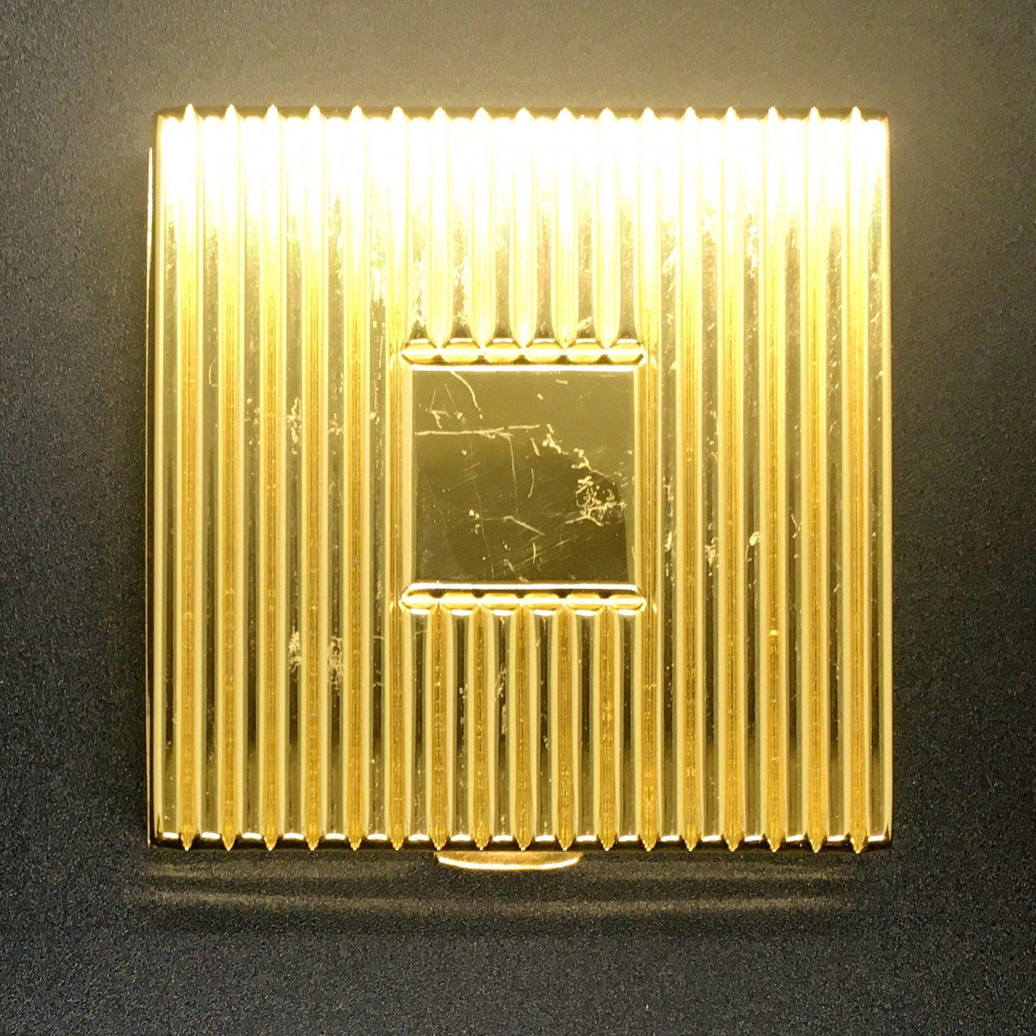 Gold compact with vertical ribbed pattern and rectangular center detail