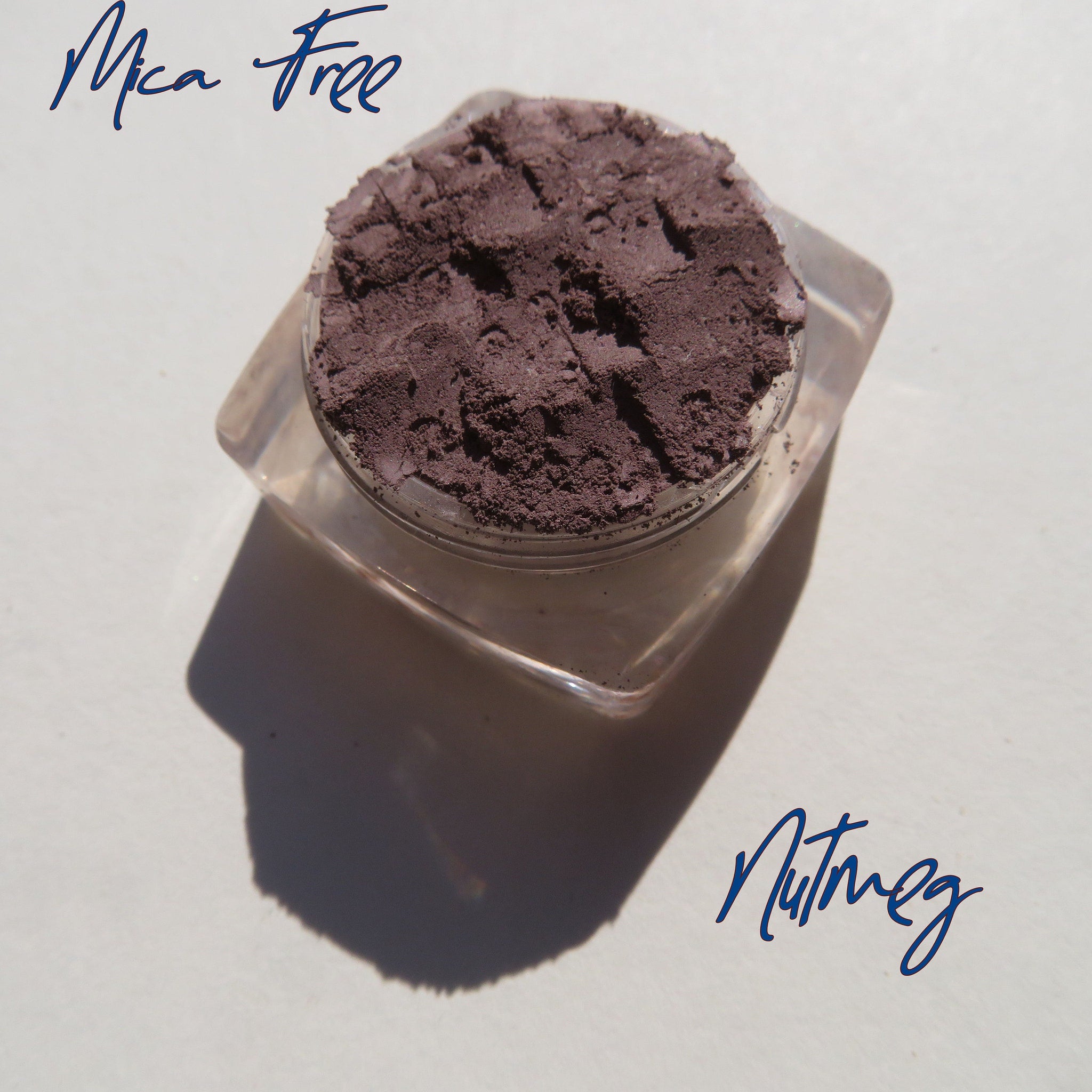 Open compact showing matte nutmeg loose mineral eyeshadow with vegan eco-friendly label on sleek black packaging