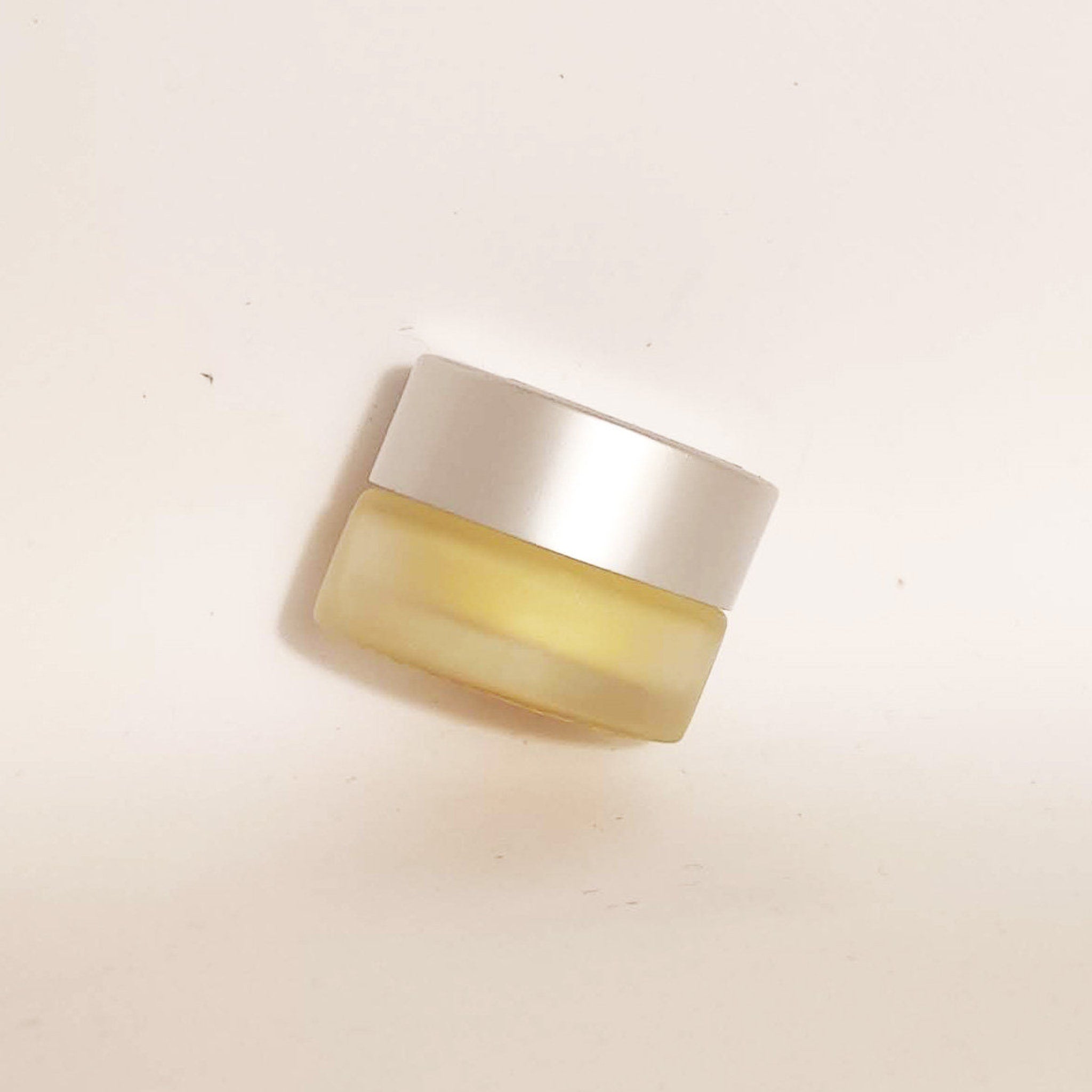 Jar of cream with silver lid, yellow glass, and minimalist style