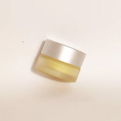 Jar of cream with silver lid, yellow glass, and minimalist style