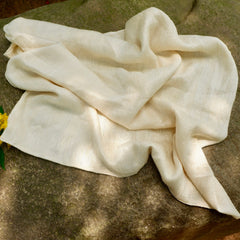 Cream-colored silk scarf with textured weave, draped on a rock surface