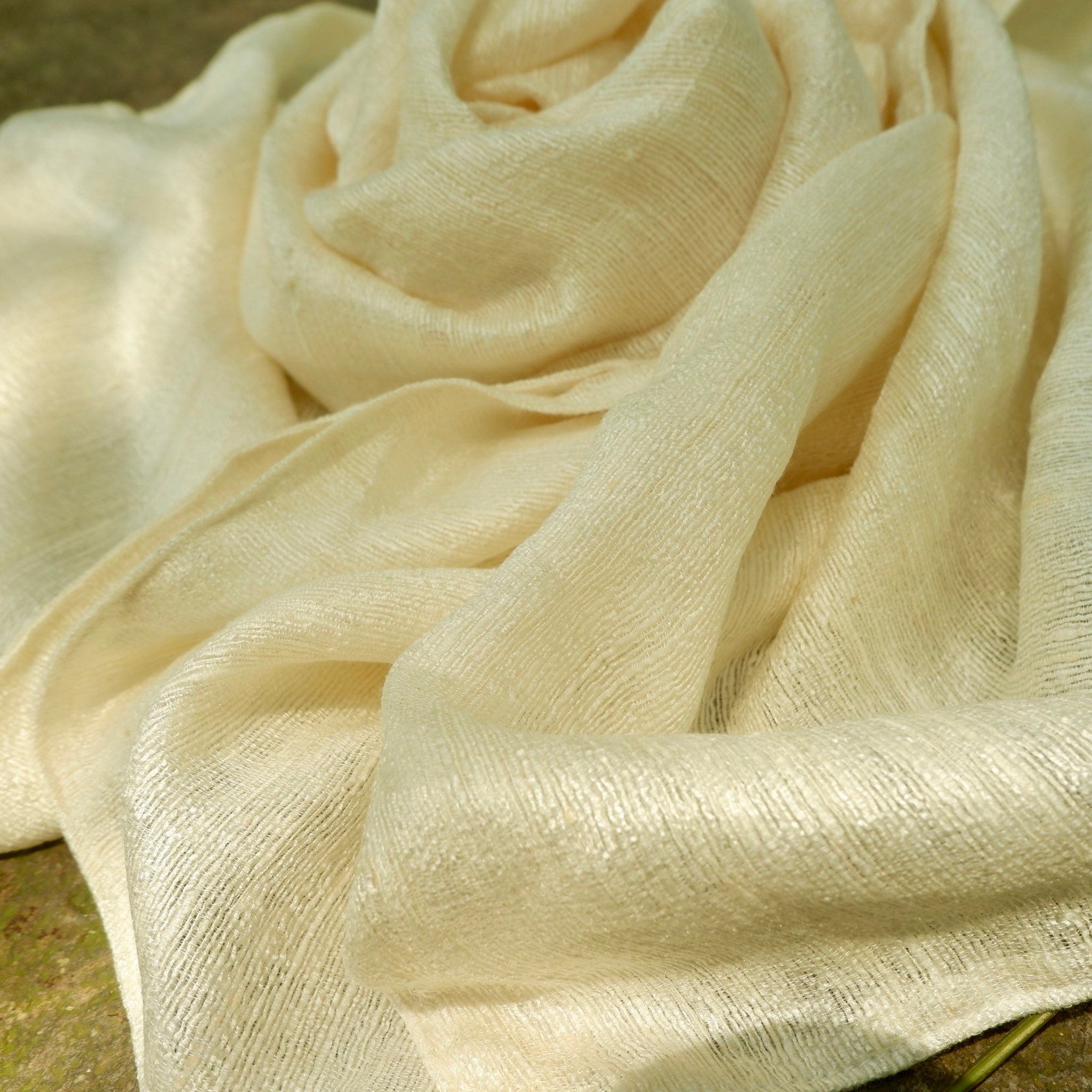 Cream-colored scarf with woven texture and draped style