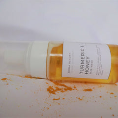 Face wash bottle with white and clear plastic, yellow liquid, and Ahima Beauty label on white surface