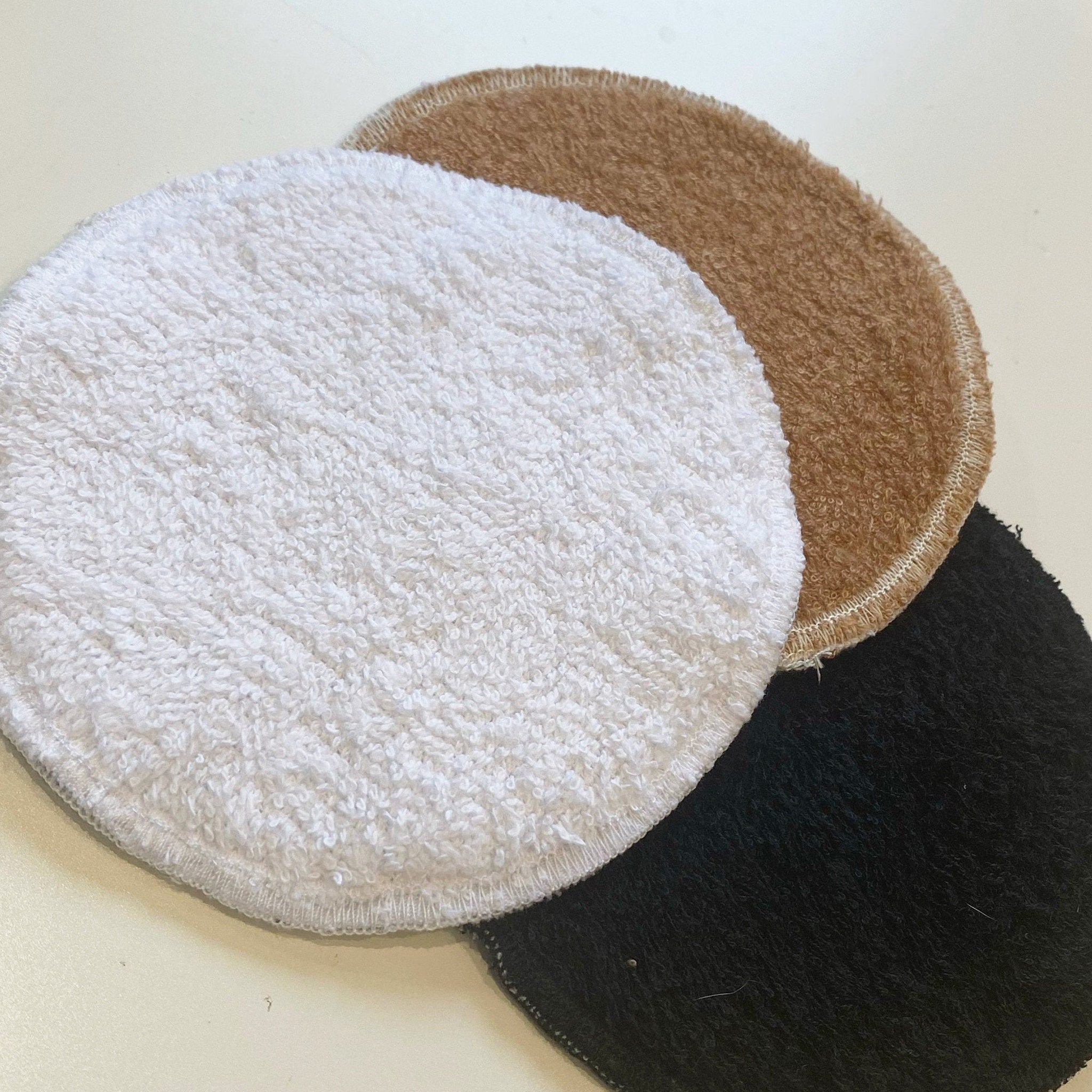 Reusable facial pads in white, brown, and black terry cloth, circular shape