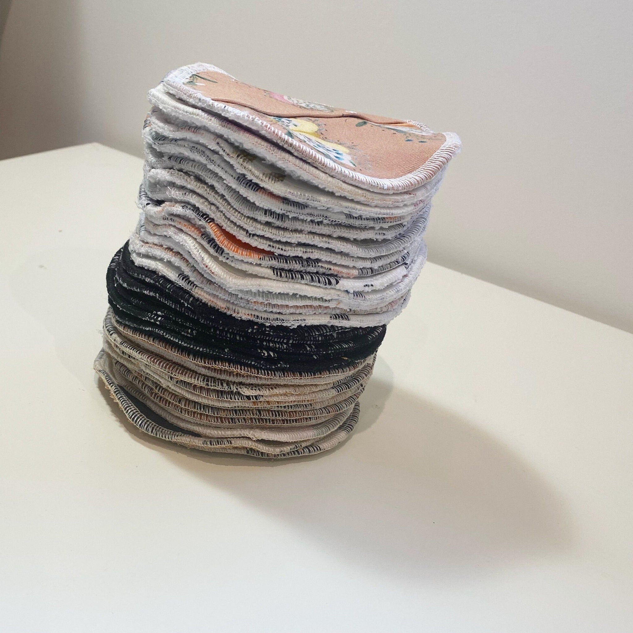 Reusable facial rounds with floral print, white trim, and stacked on white surface