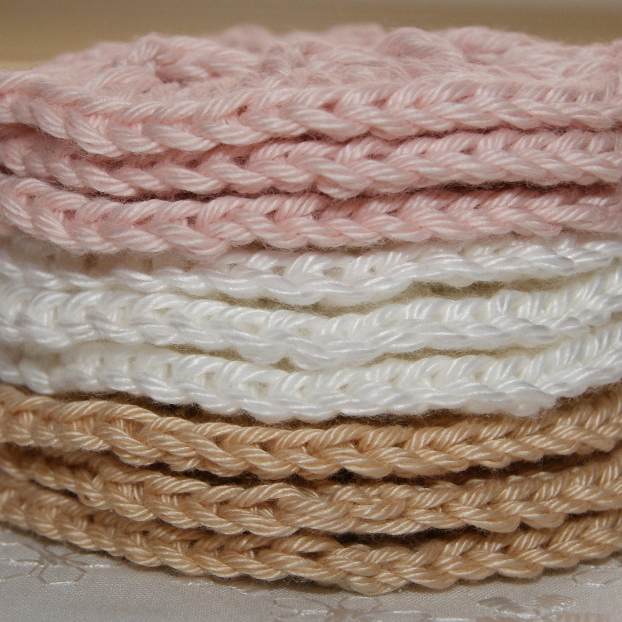 Crochet circles in pink, white, and tan colors, stacked together, close-up view