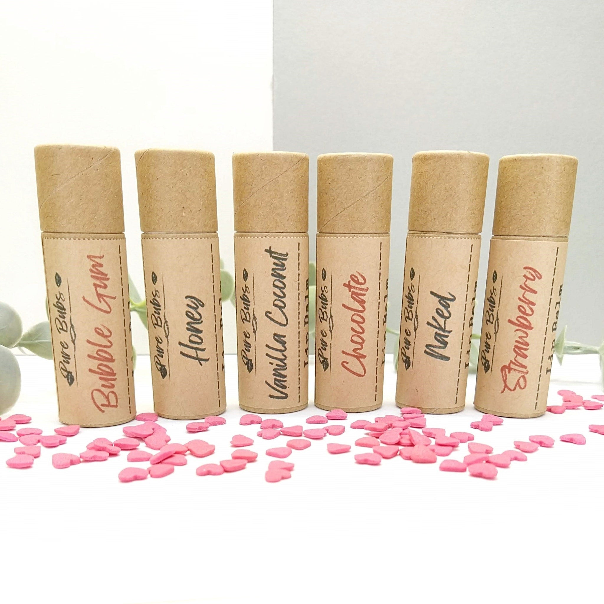 Lip balms in kraft paper tubes with flavor labels and pink heart confetti