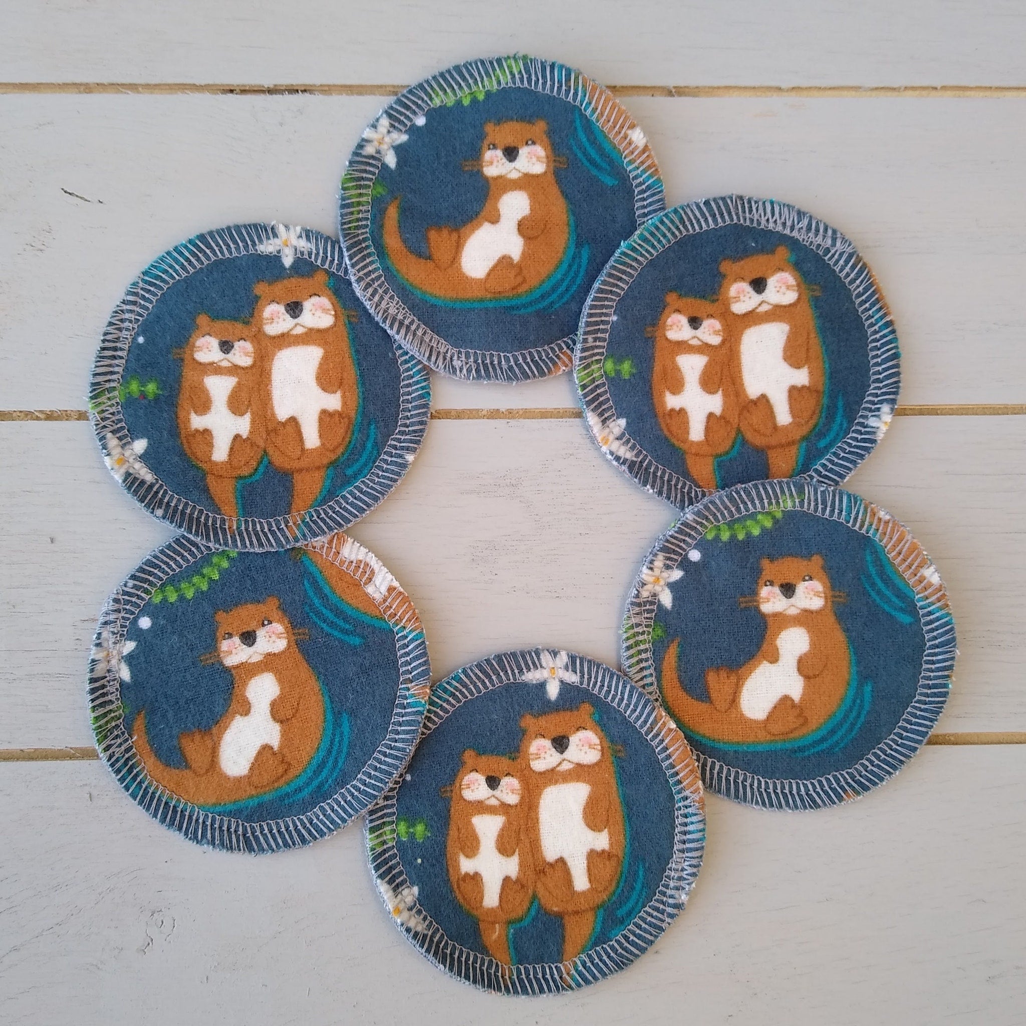 Coasters with otter print, blue fabric, white stitched edge, and floral accents
