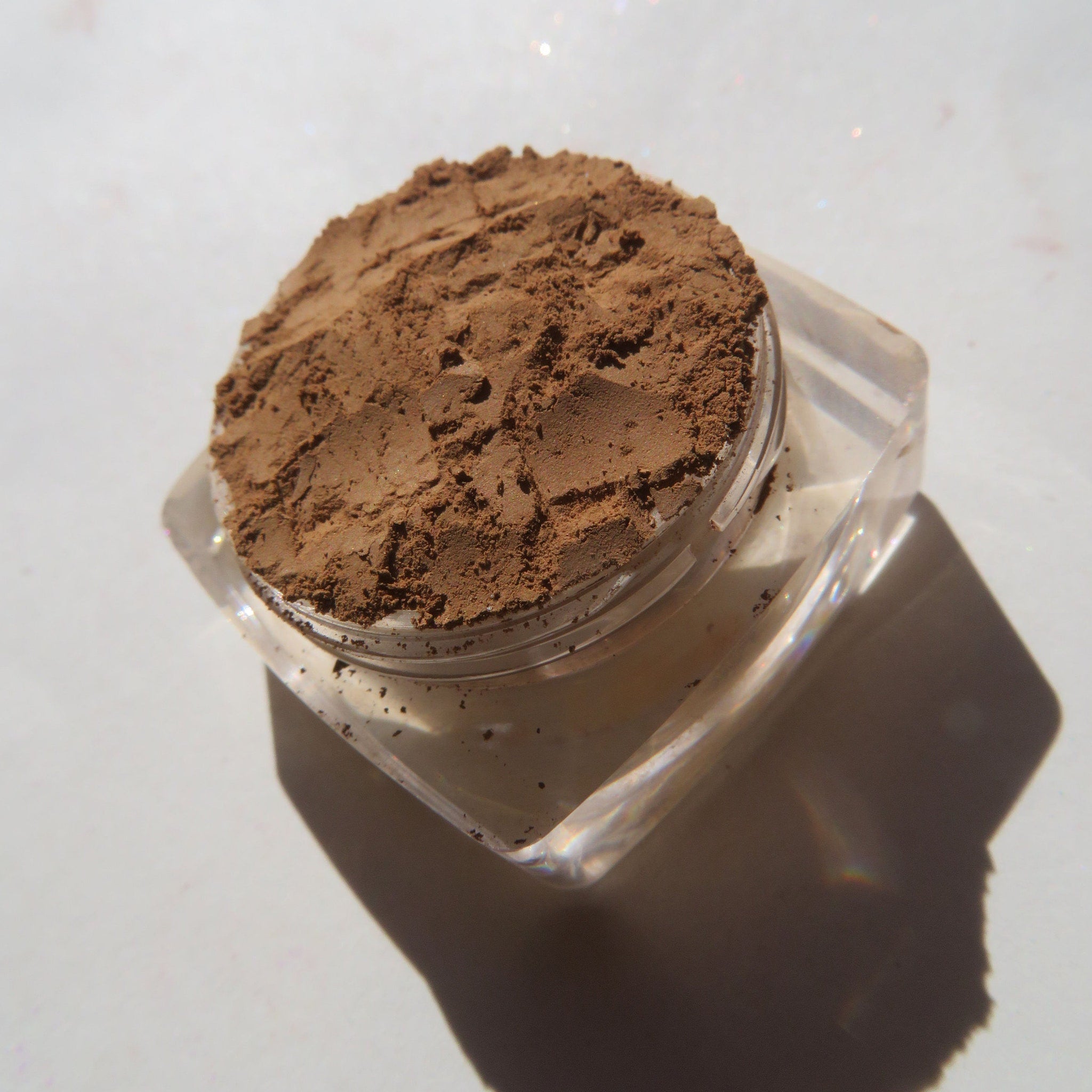 Side view of matte brown-orange mineral eye shadow in loose powder form with vegan cruelty-free label visible