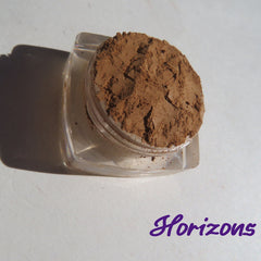 Close-up of matte brown-orange mineral eye shadow in loose powder form with vegan, cruelty-free label