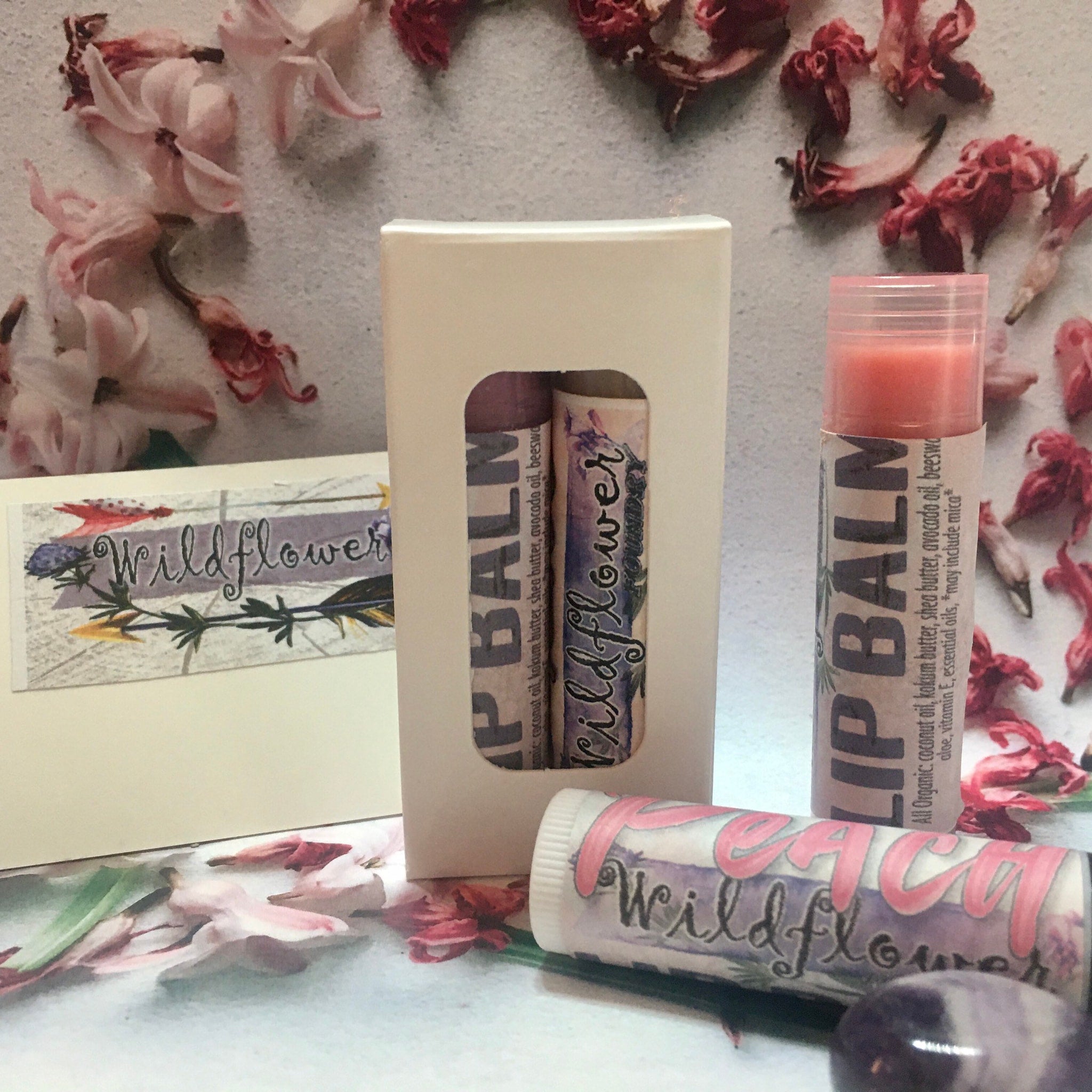 Lip balm tubes with "Wildflower" text, pink and purple floral pattern, in a gift box