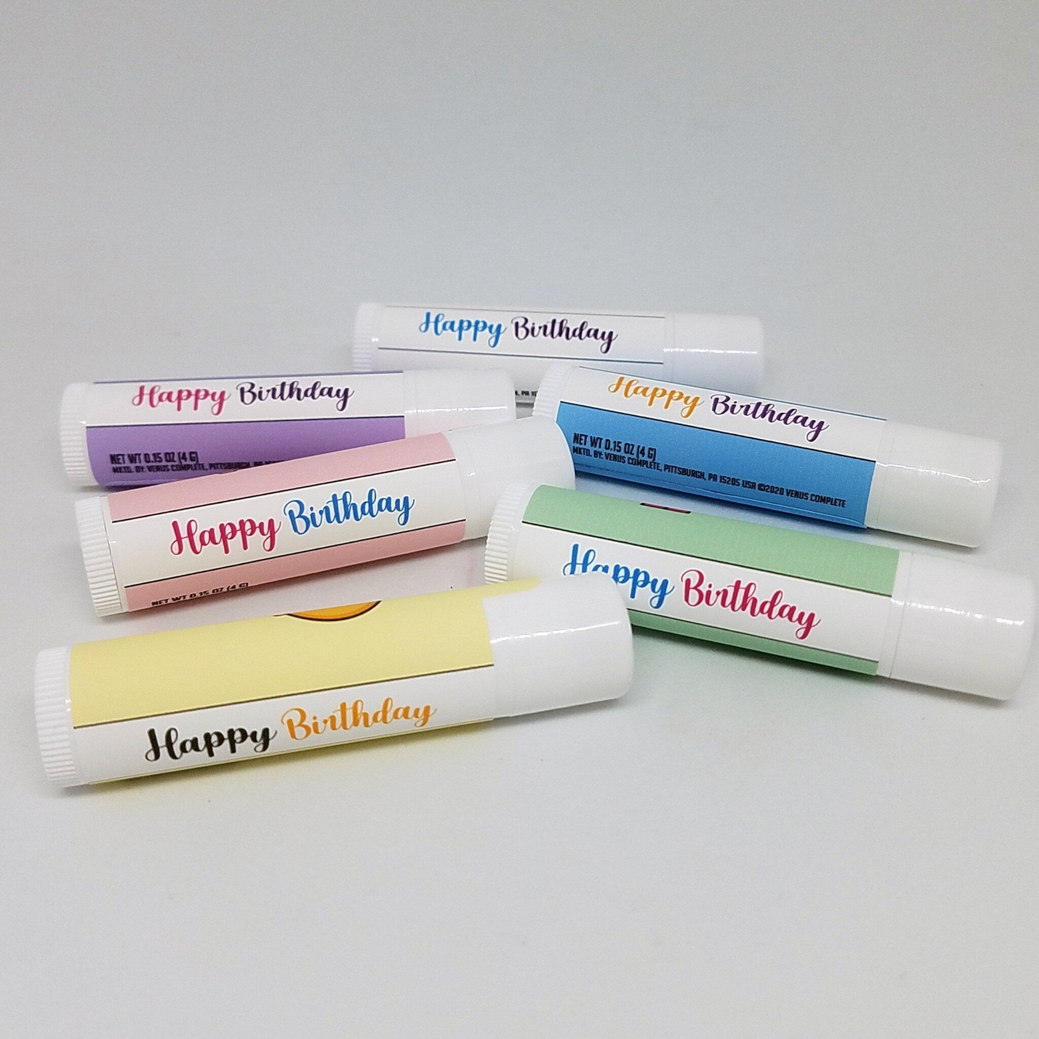 Lip balm tubes with "Happy Birthday" text in various colors and styles, Venus Complete brand