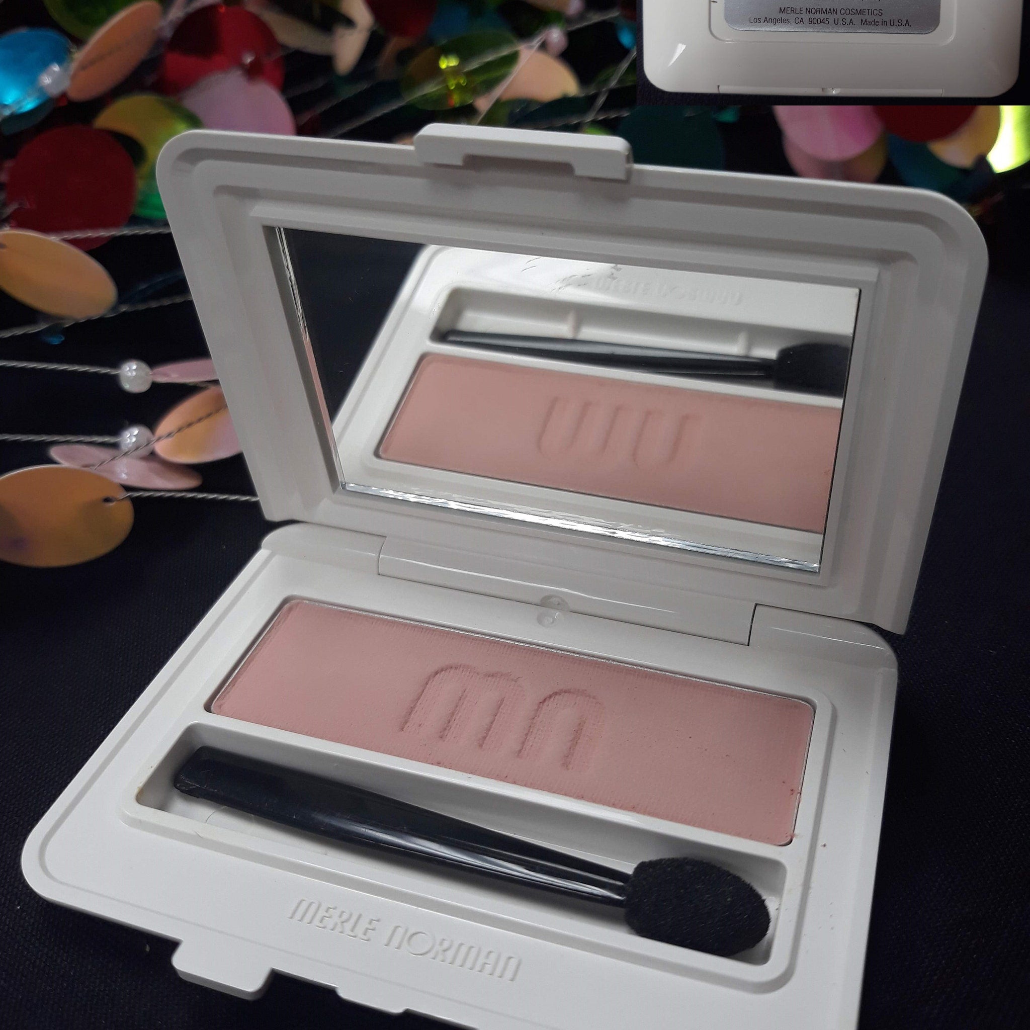 Close-up of Merle Norman Luxiva single eye shadow compact in shimmering plum with gold flecks