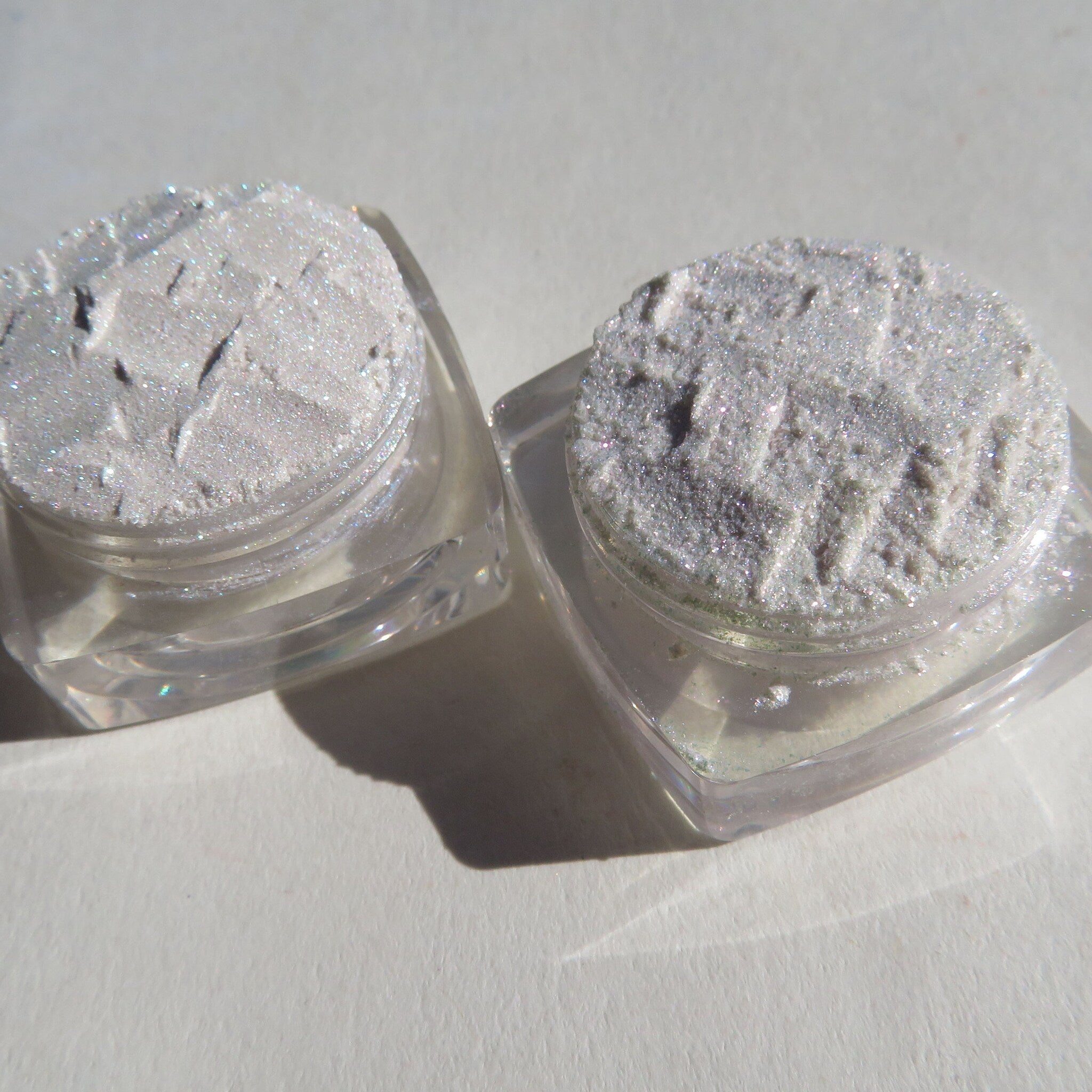 Hand applying shimmery loose powder eyeshadow with a brush, showcasing vibrant pigment blendability