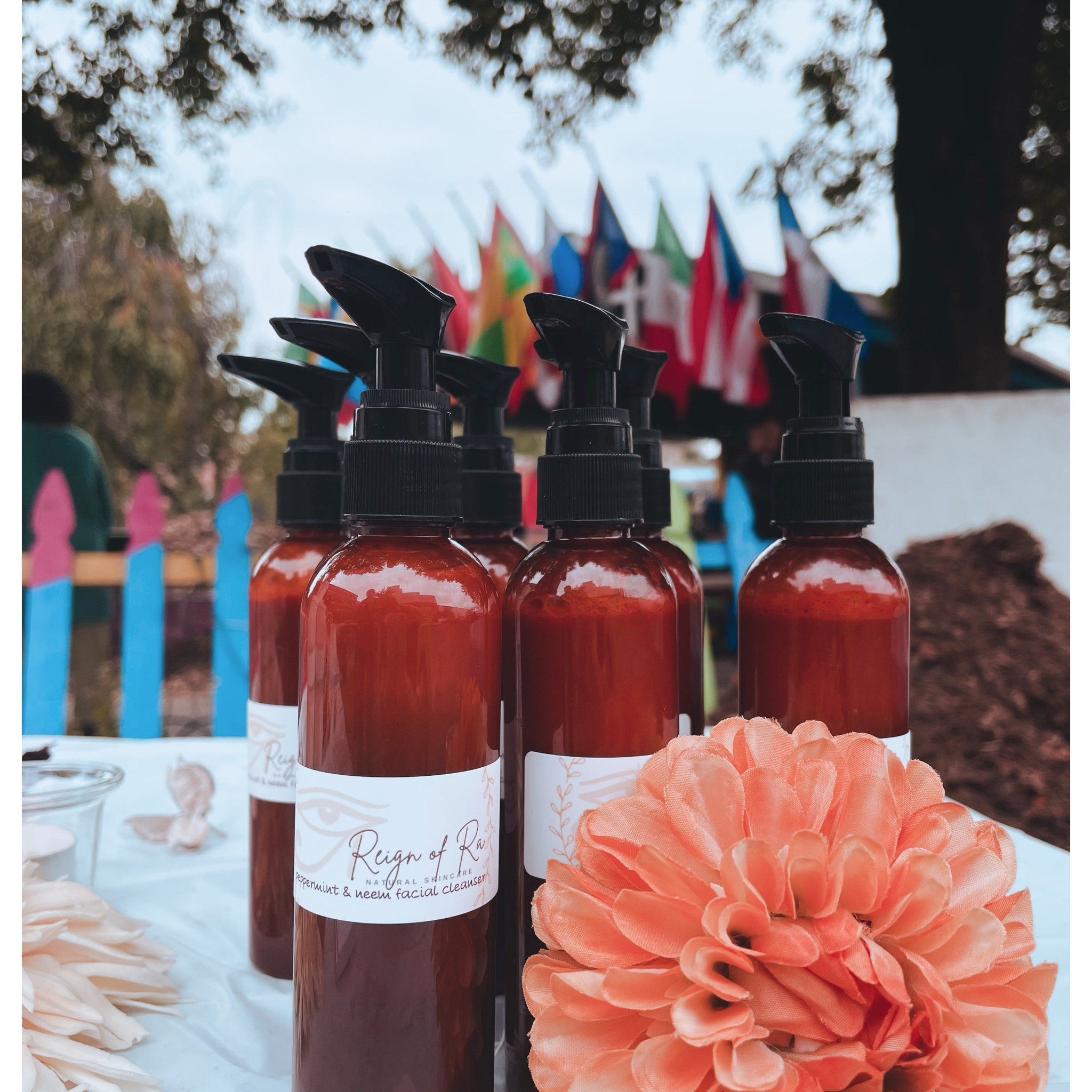 Facial cleanser bottles, brown glass with black pump, Reign of Ra brand shown with flower
