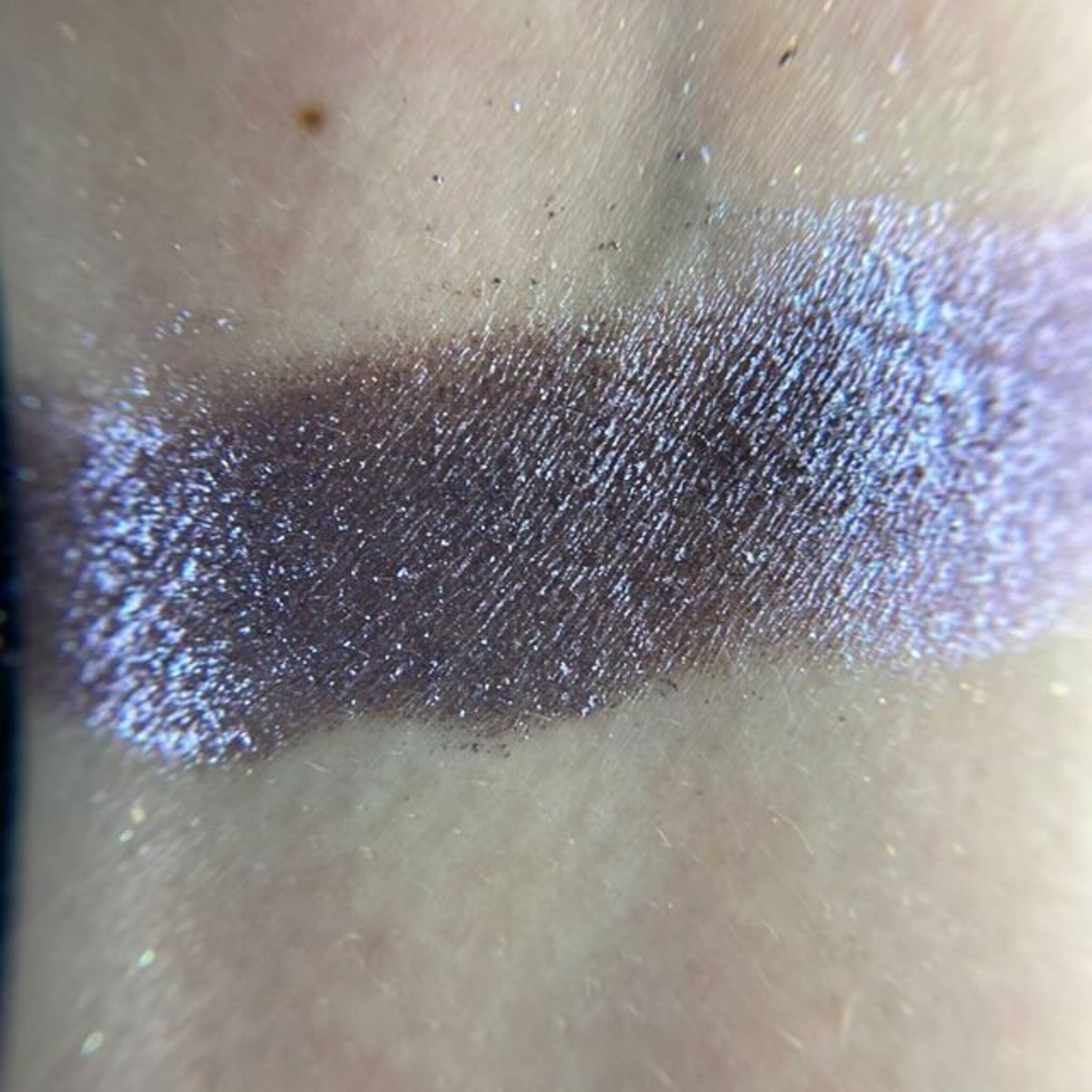 Close-up of fingertips applying shimmery bronze eyeshadow from the palette to eyelid