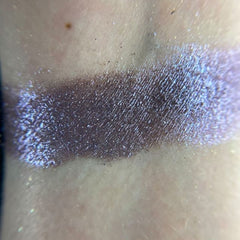Close-up of fingertips applying shimmery bronze eyeshadow from the palette to eyelid