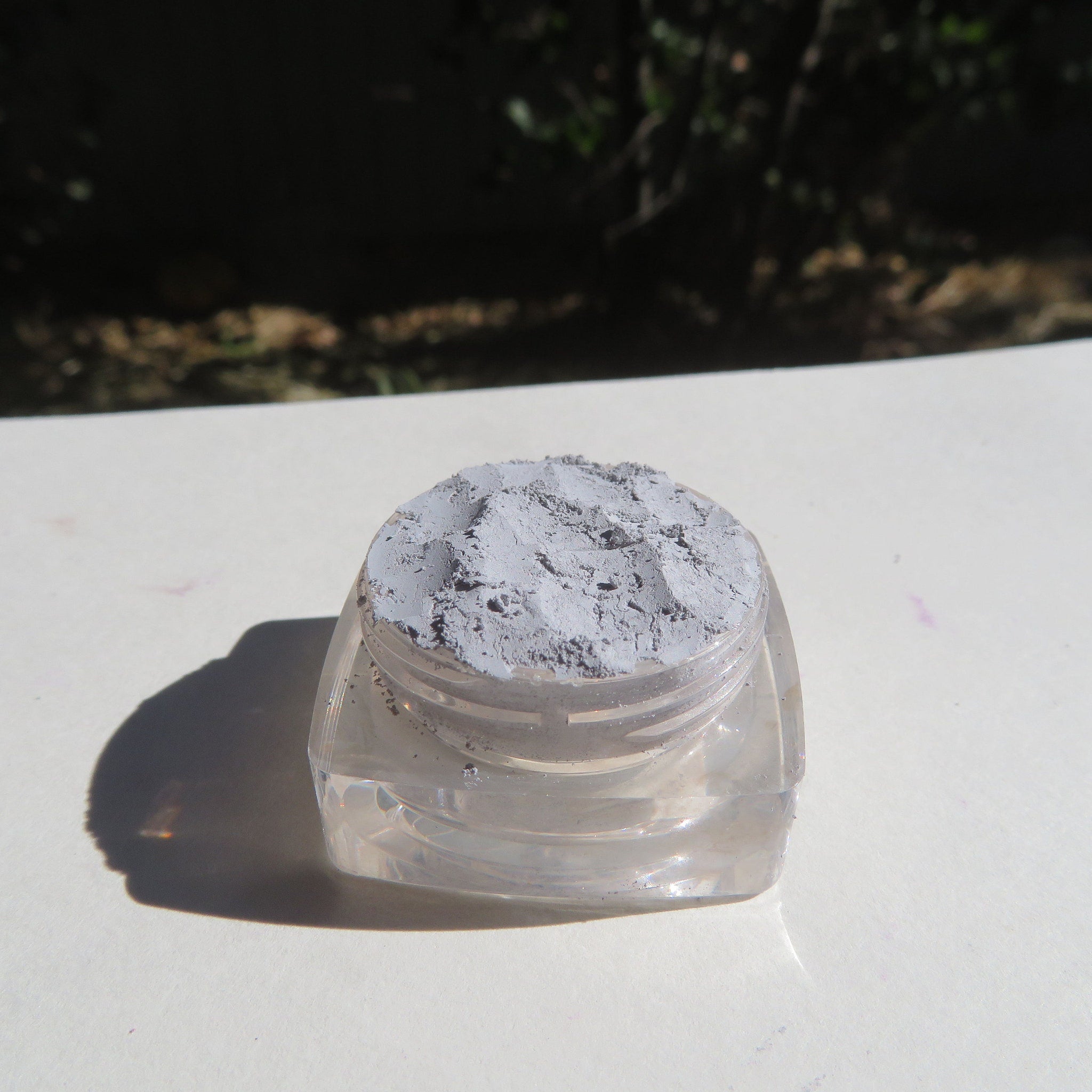 Side view of matte gray Titan loose pigment eyeshadow in eco-friendly packaging, showcasing texture and mica-free formula