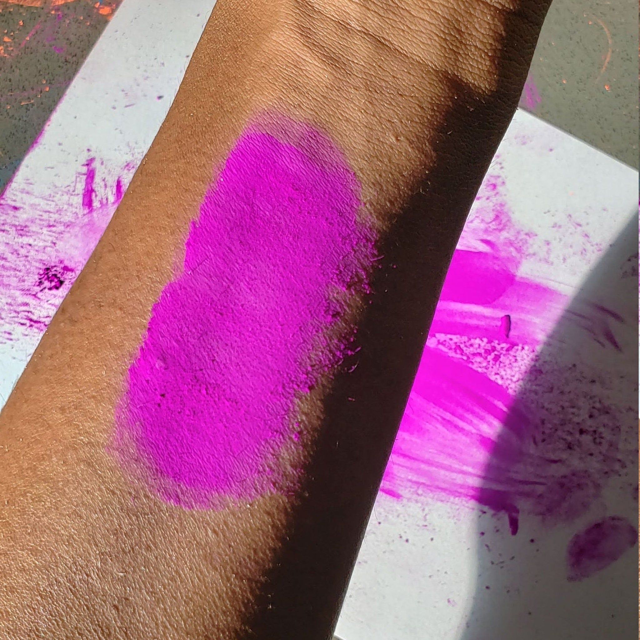 Vibrant neon purple eyeshadow pot with UV glow effect, perfect for festival makeup looks
