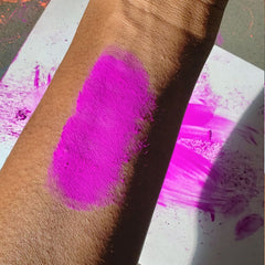 Vibrant neon purple eyeshadow pot with UV glow effect, perfect for festival makeup looks