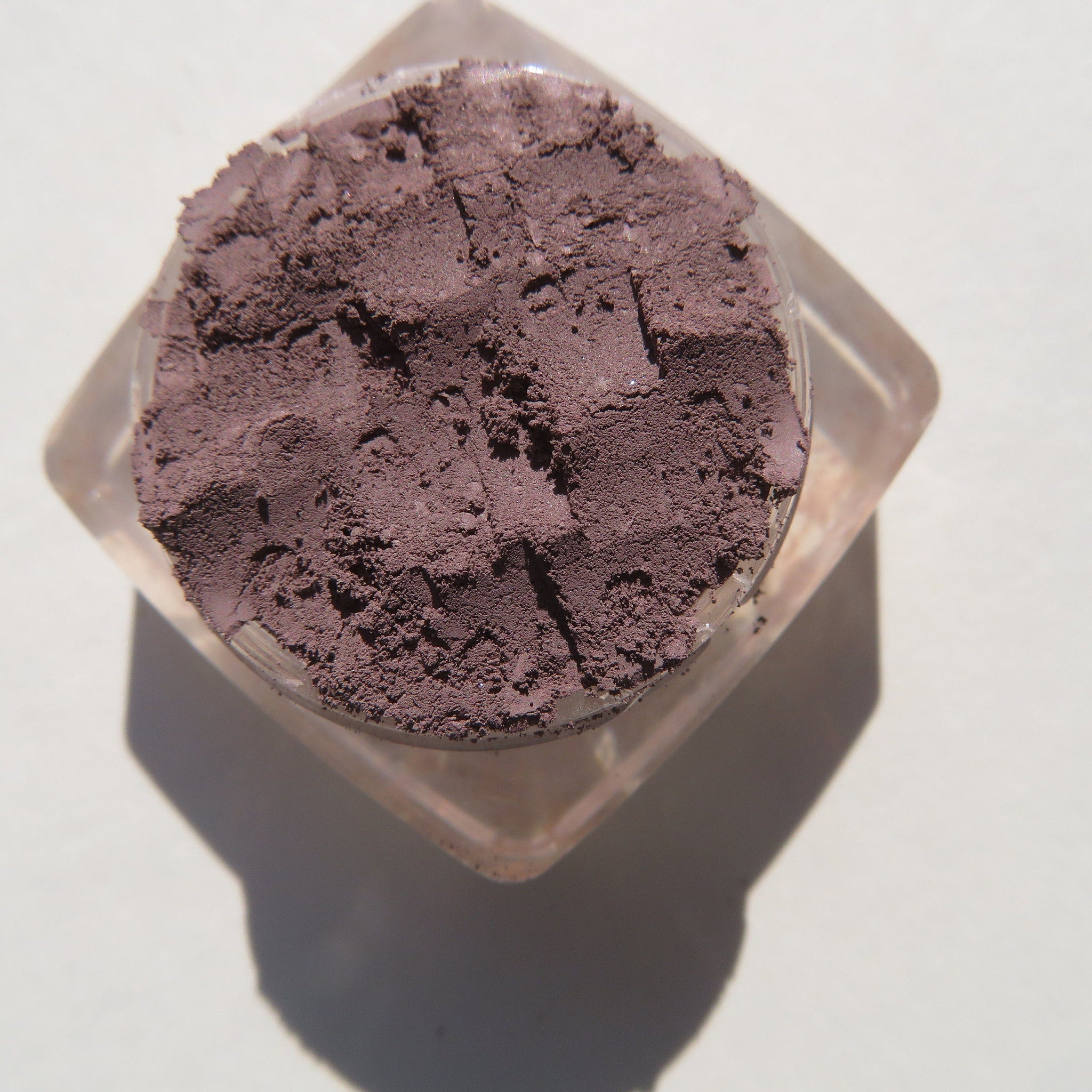Close-up of matte nutmeg loose mineral eyeshadow with fine powder texture in eco-friendly packaging