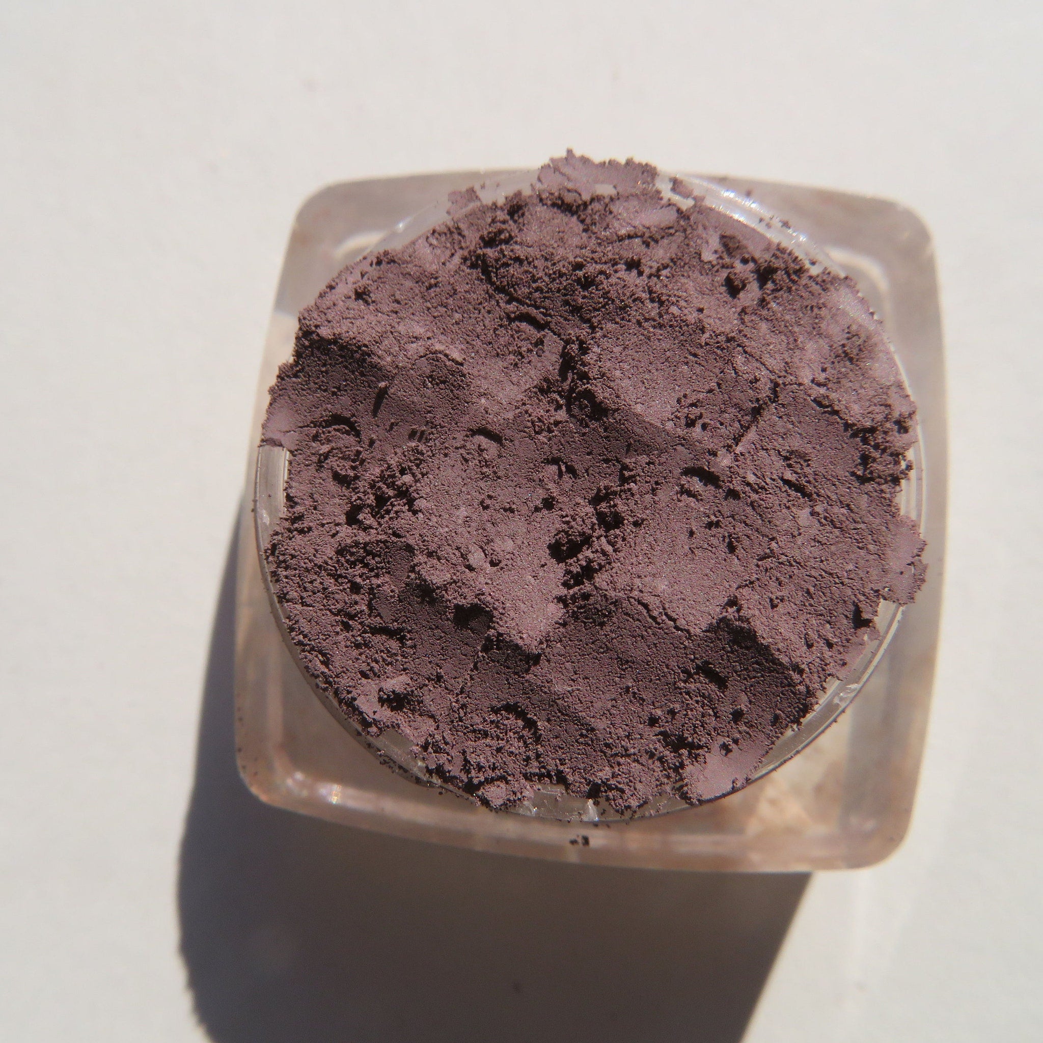 Side view of matte nutmeg loose mineral eyeshadow in eco-friendly jar with sifter lid, showcasing texture and depth.