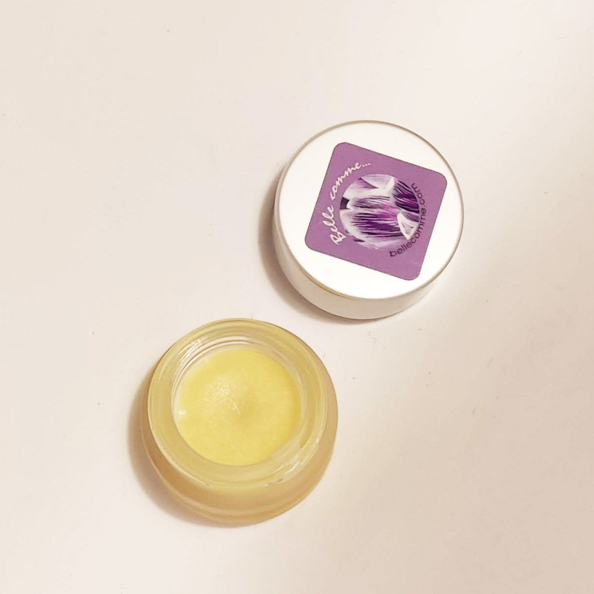 Lip balm in clear glass jar with yellow balm and Belle comme logo on lid