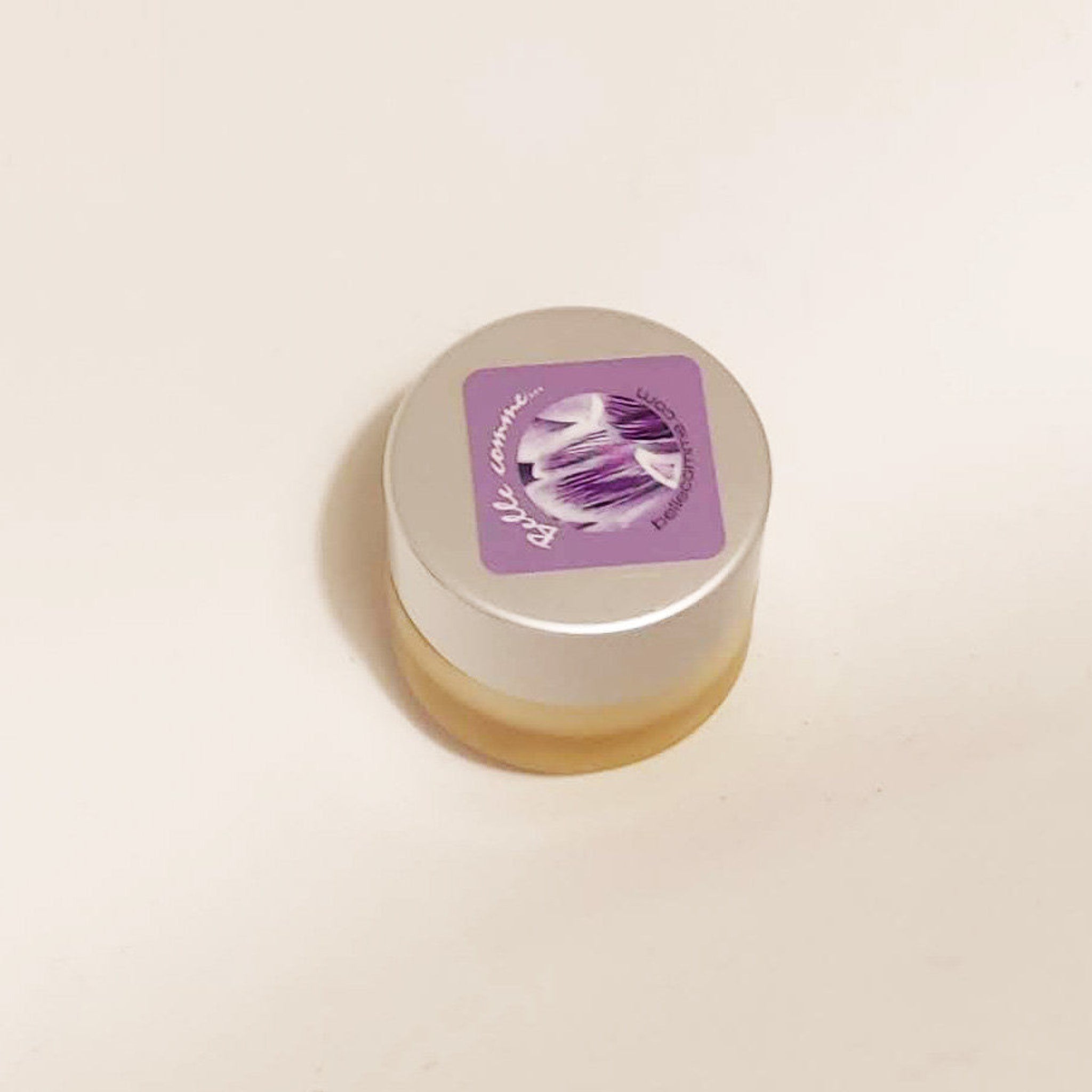 Cosmetic jar with silver lid, purple label, and clear contents