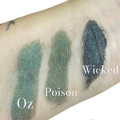 Side view of emerald green mineral eyeshadow in petite glass jar with gold lid, showcasing rich pigment texture