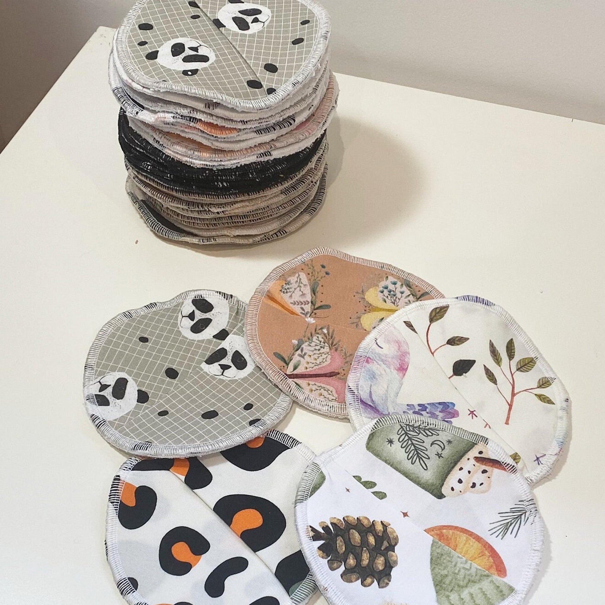 Reusable nursing pads with various patterns and colors, stacked on white surface, Lenas Yard