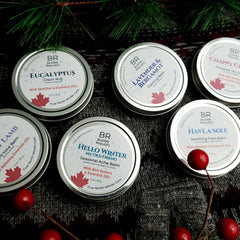 Body balms in silver tins with text, Bubble Republic brand on gray sweater background