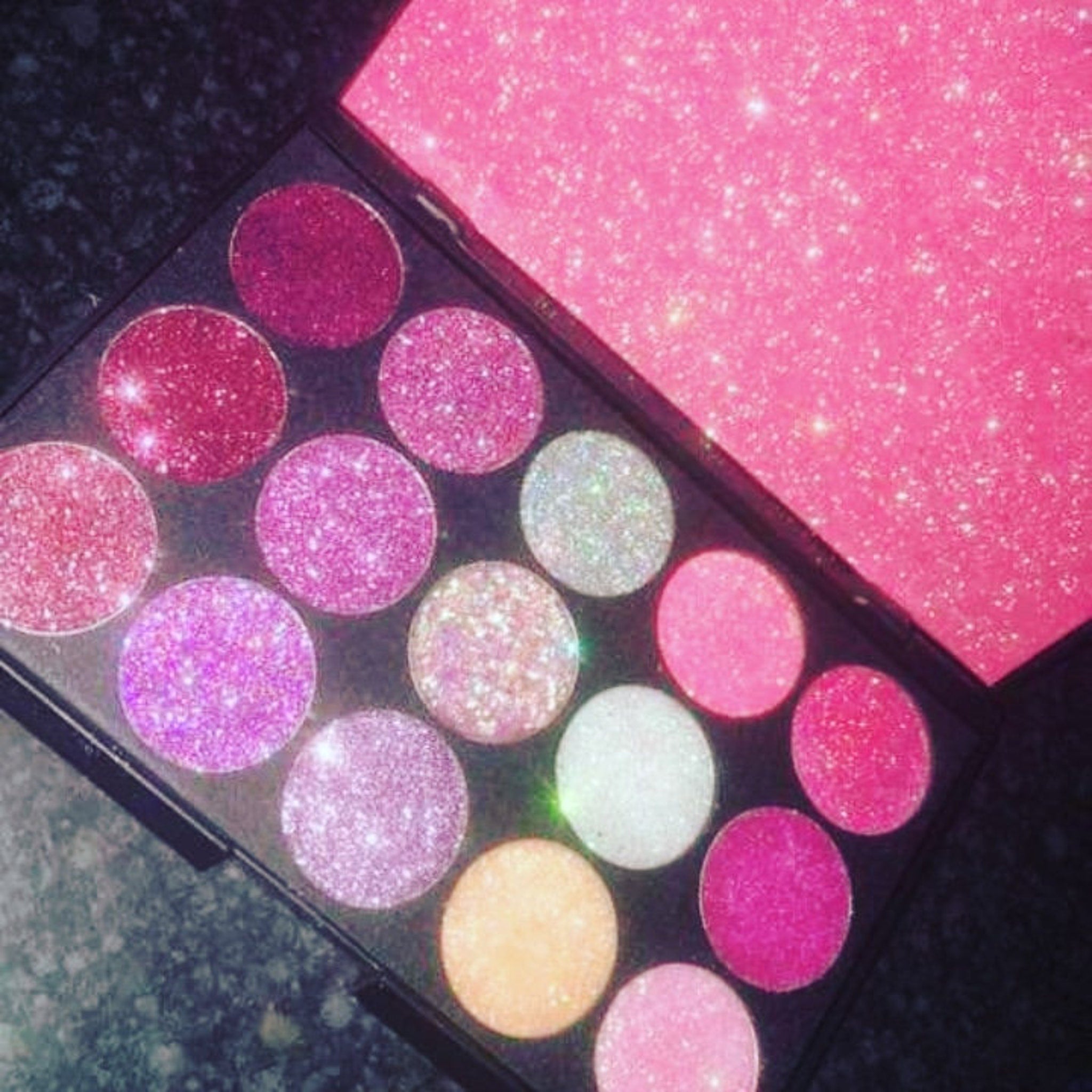 Glitter eye shadow palette with sleek black compact and mirrored interior, showcasing vibrant shimmer shades.