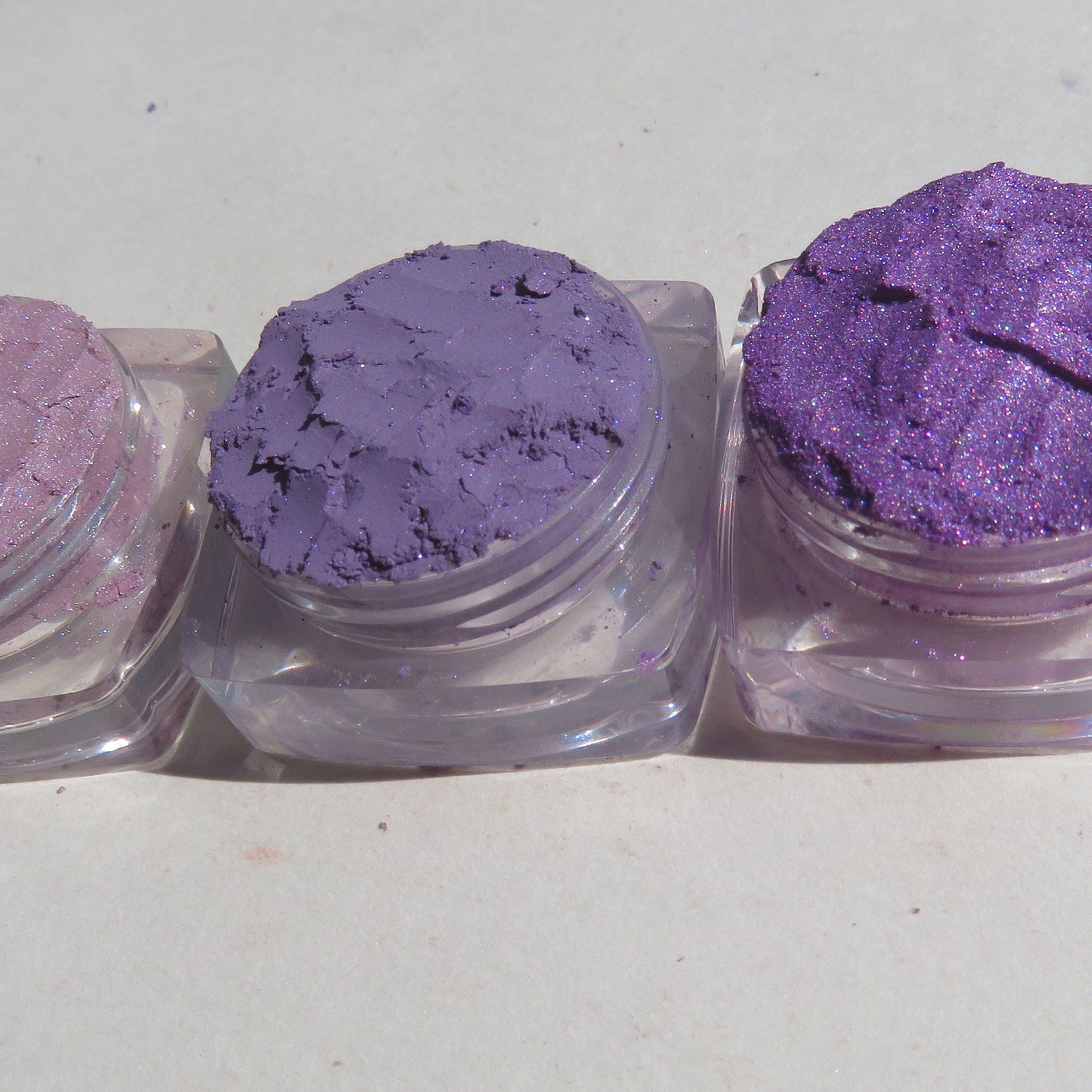 Close-up of three shimmering purple loose mineral eyeshadows with vegan sparkly pigments in a gift set