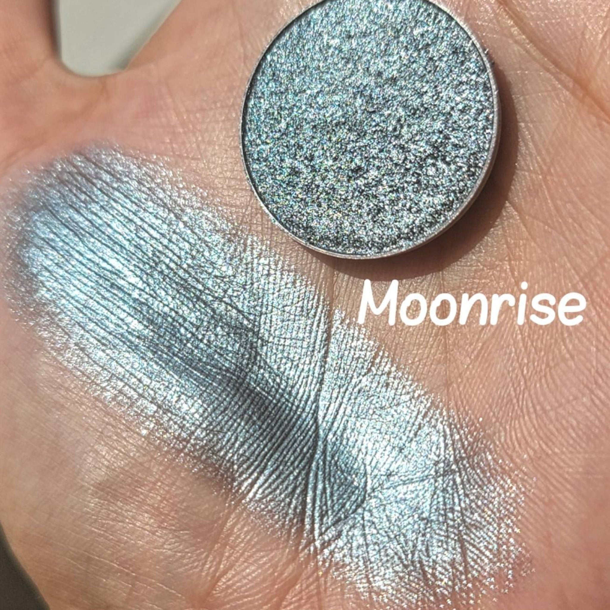 Extreme close-up of Moonrise Chameleon Eye Shadow showing icy blue to grey color shift with sparkling shimmer particles