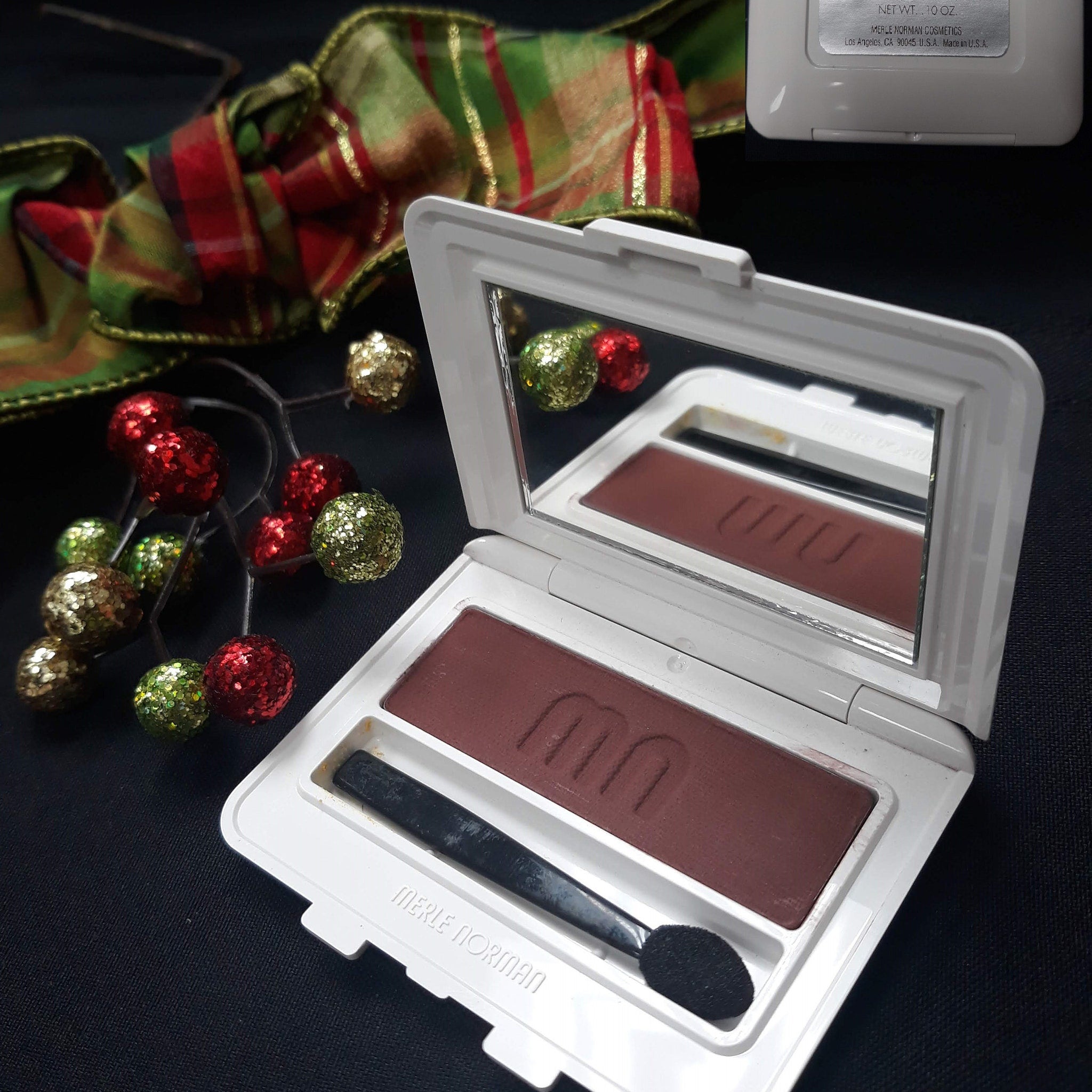 Side view of Merle Norman Luxiva single eye shadow compact showing rich brown shade in matte finish with gold trim
