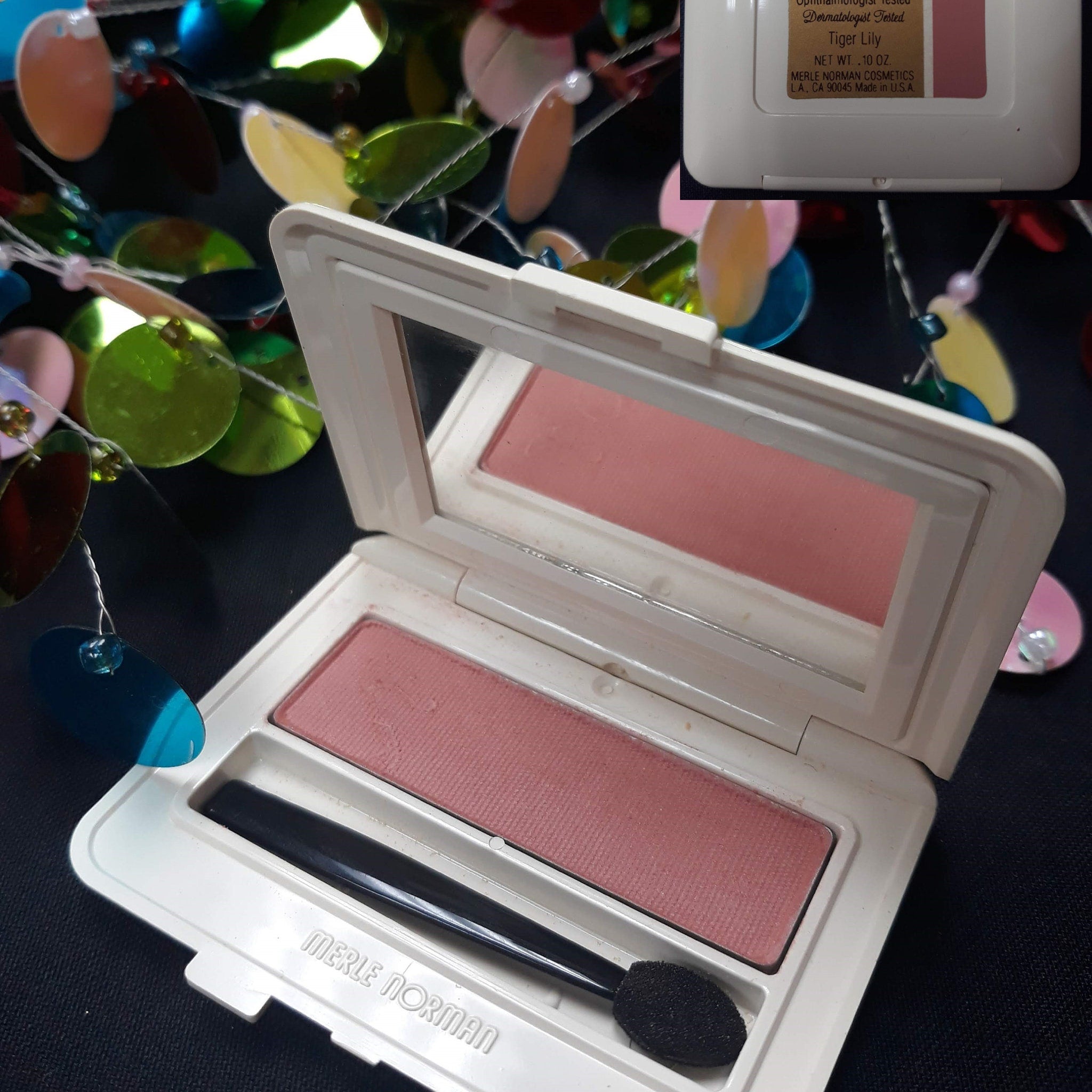 Side view of Merle Norman Luxiva single eye shadow compact showing rich brown, pink, and purple shades in square pan