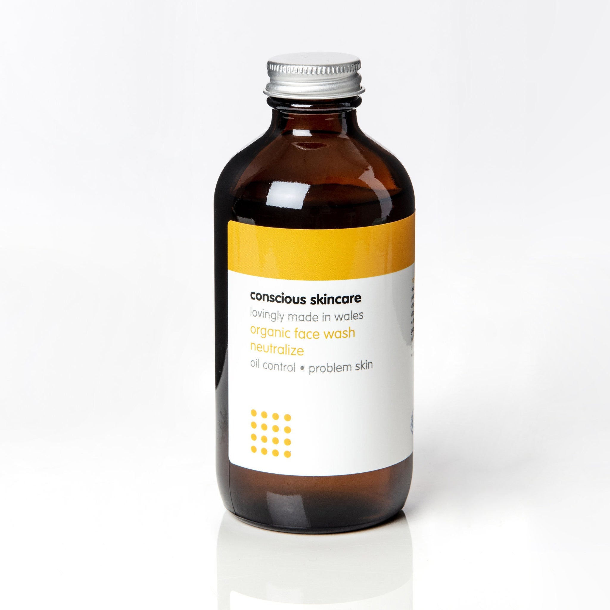 Face wash bottle with brown glass, silver cap, and Conscious Skincare label with yellow accent