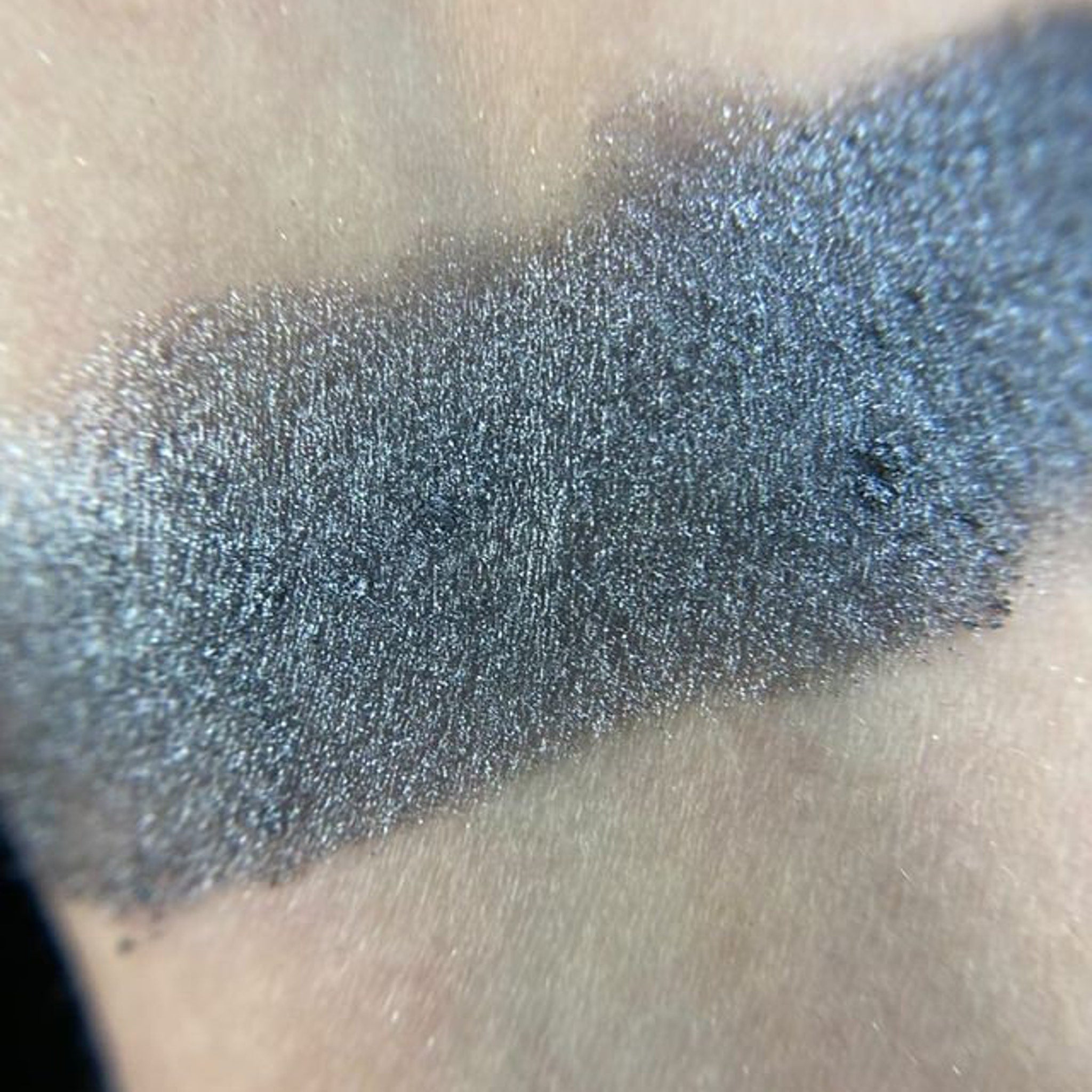 Close-up of matte gray-taupe eye shadow pan with smooth pressed powder texture in black compact