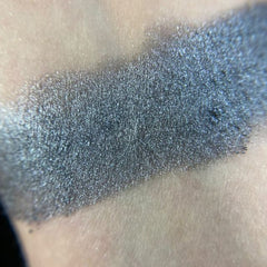 Close-up of matte gray-taupe eye shadow pan with smooth pressed powder texture in black compact