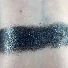Close-up of six shimmering eyeshadow pans in bronze, gold, rose, plum, taupe, and navy with metallic finishes