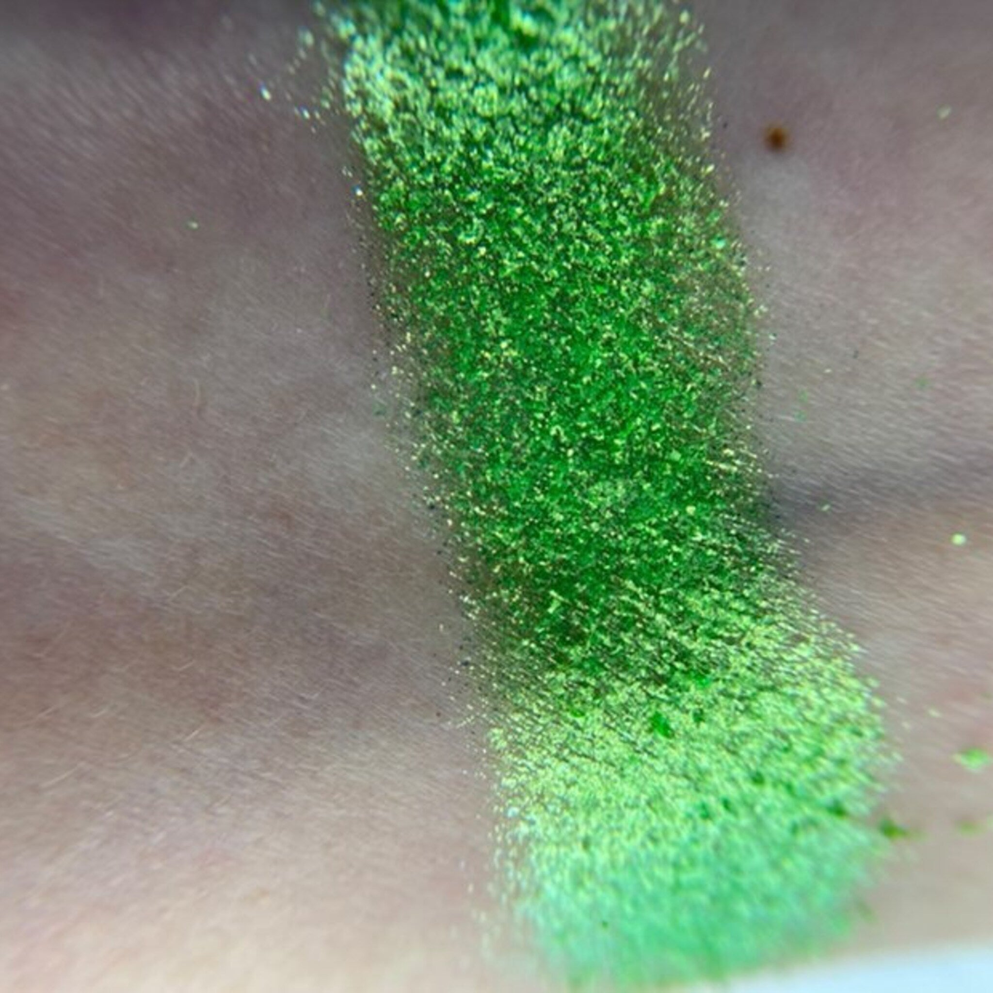 Close-up of shimmering bronze eyeshadow pan with embossed logo, showcasing rich metallic finish