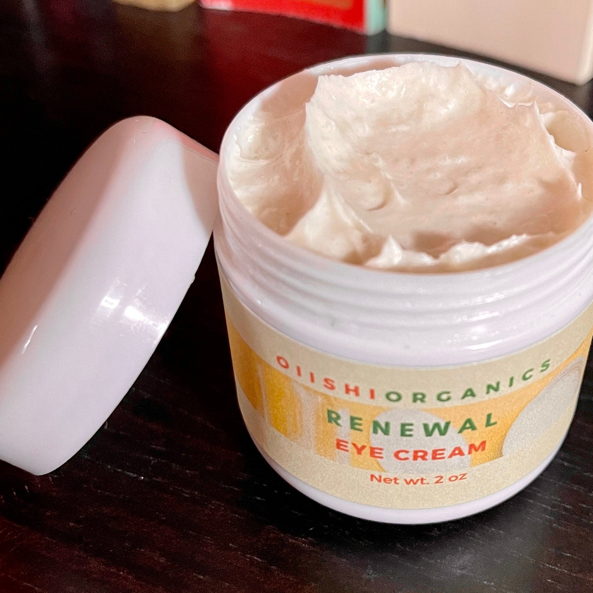 Eye cream in white jar with OIIISHIORGANICS label, white cream, open lid on table