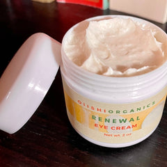 Eye cream in white jar with OIIISHIORGANICS label, white cream, open lid on table