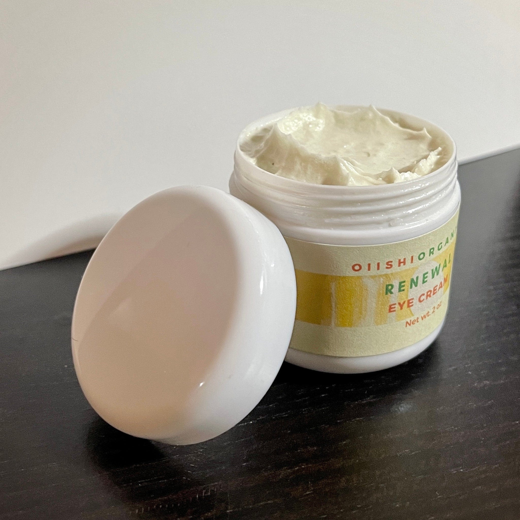 Eye cream jar with white and yellow label, white lid, and light green cream inside
