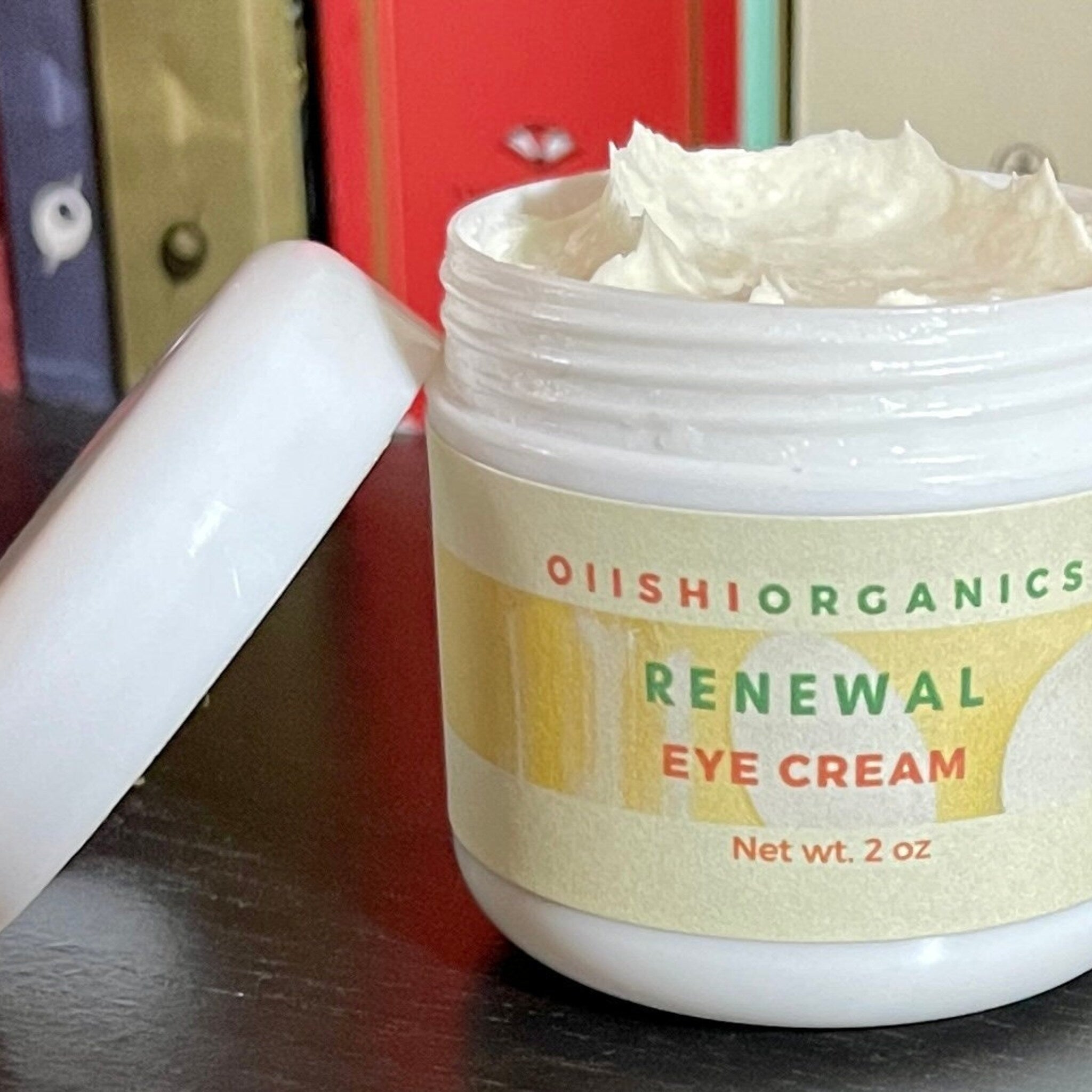 Eye cream jar with white cream, white jar, and OIIISHIORGANICS label visible