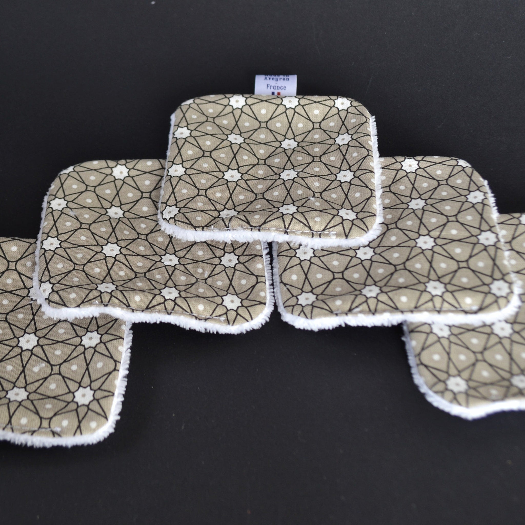 Reusable face pads with geometric pattern, tan fabric, white trim, Avegron France label visible