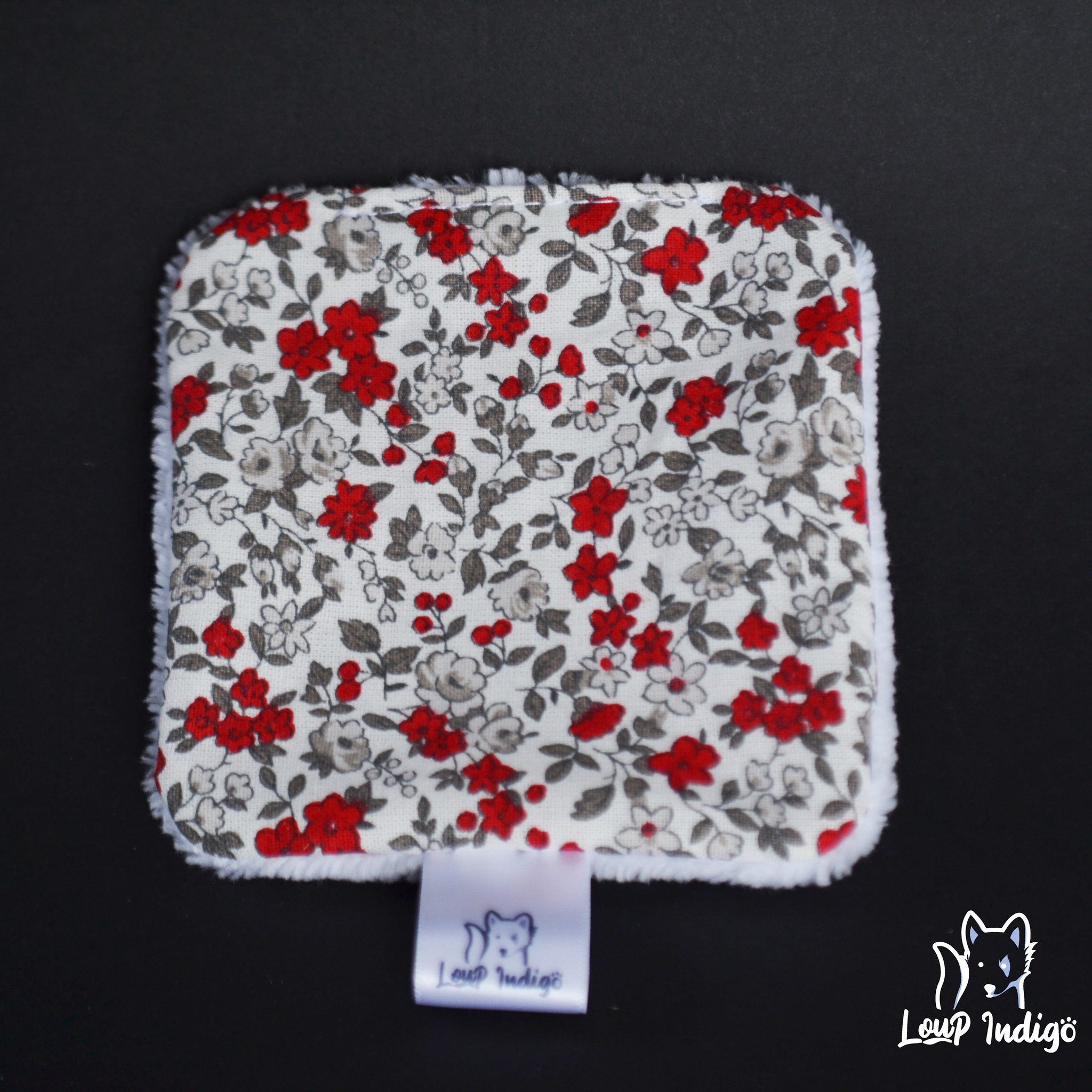 Floral print fabric square with red, white, and gray flowers, white trim, and "Loup Indigö" brand label