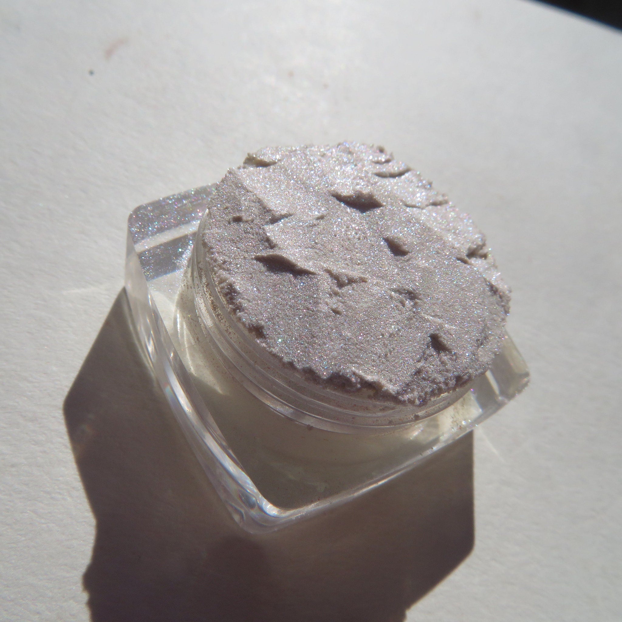 Open jar of Twisted Mineral Eyeshadow showing loose sparkly pigment in vibrant shimmering hues