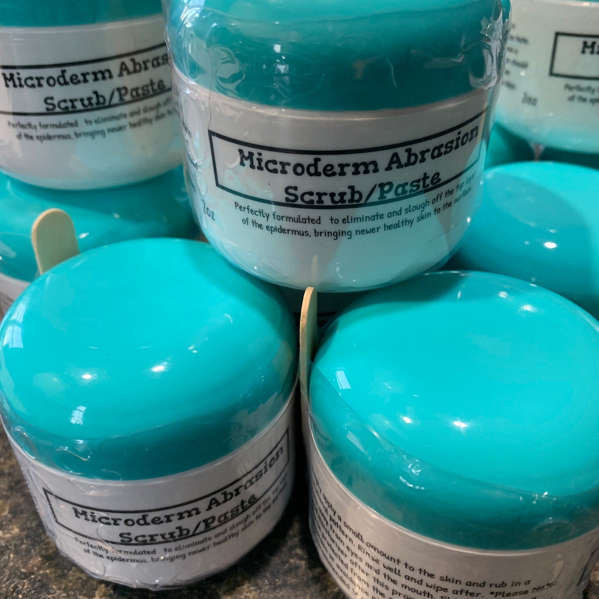 Microderm Abrasion Scrub/Paste, teal plastic jar with white label, wooden applicator visible