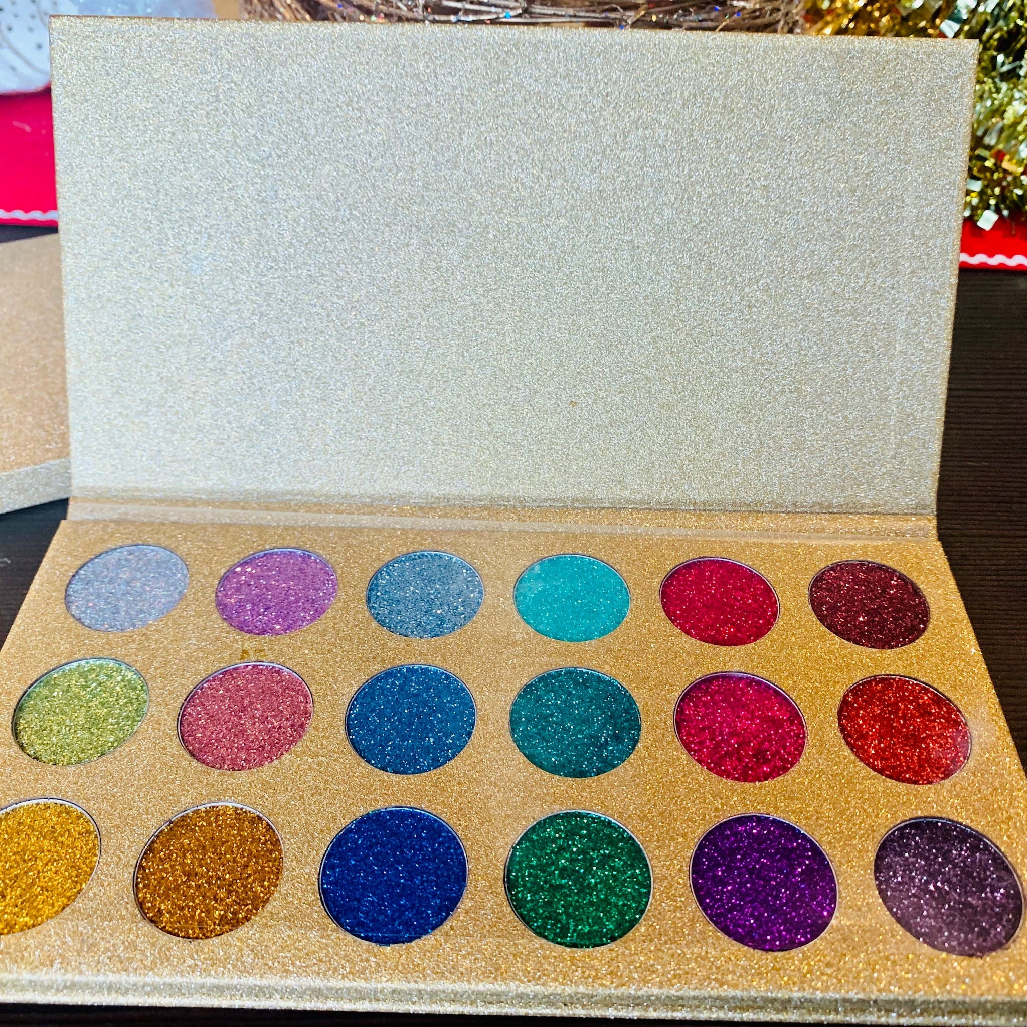 Eyeshadow palette with gold glitter case and various colorful glitter eyeshadows